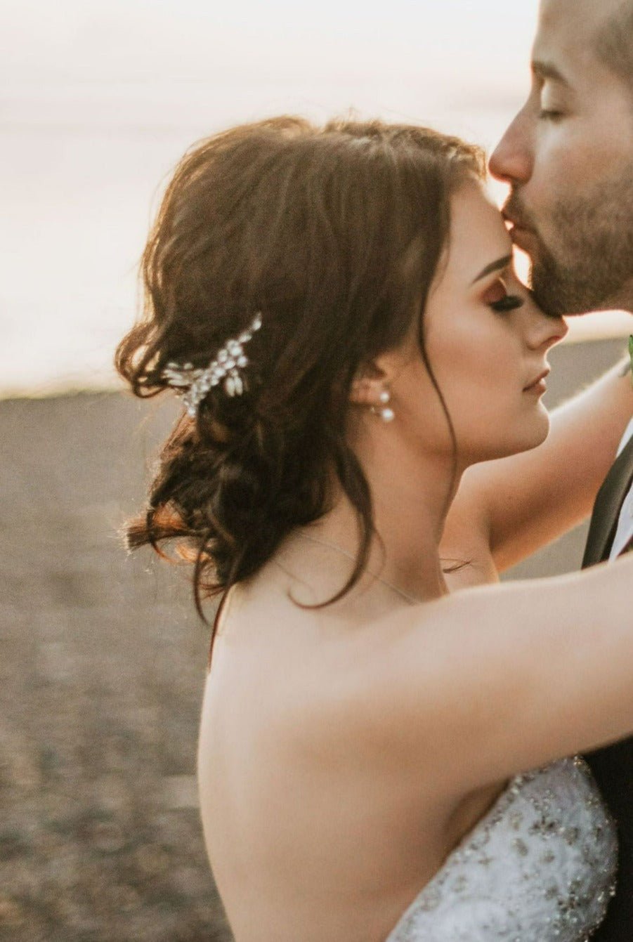 A groom kisses his bride's forehead. Her silver crystal bridal hair crown accentuates her dark curly hair with crystals. Bridal Hair Accessories. Bridal Accessories. Canadian Bridal Accessories. Handmade Canadian Accessories. Canadian handmade Accessories. Canadian weddings. Wedding Canada. 