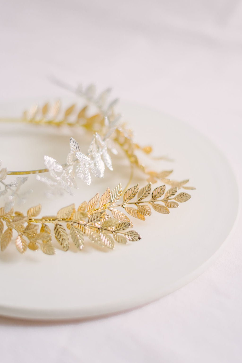 Two bridal hair accessories in silver and gold with laurel leaves.