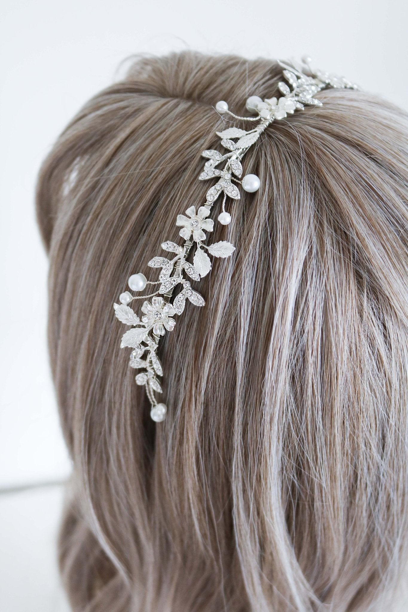 Astoria crystal and pearl bridal headband in silver sits in the hair of a display head bust. 