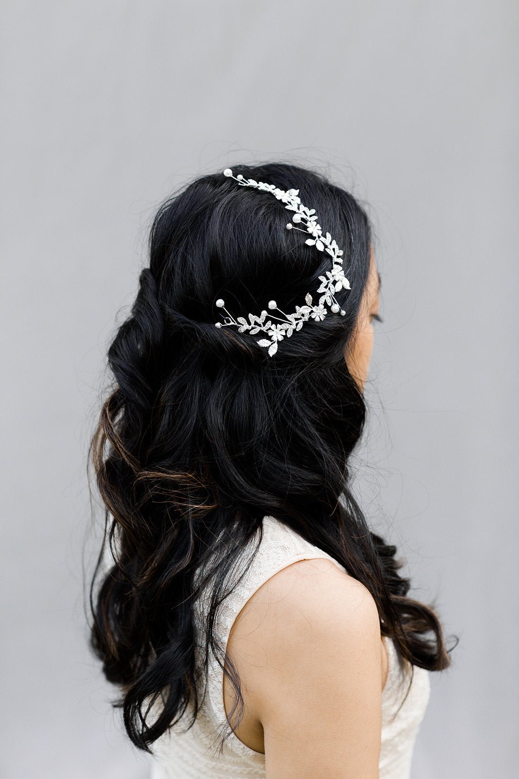 Gorgeous bridal hair accessory hairvine in silver has freshwater pearls and crystals and drapes across a bride's dark hair. 