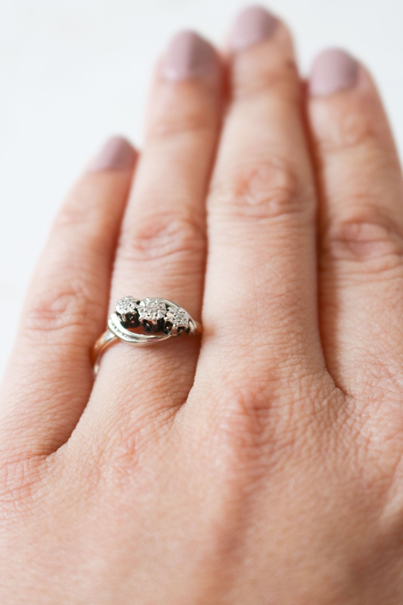 A vintage engagement ring in 18ct gold and platinum with diamonds is worn on a finger.