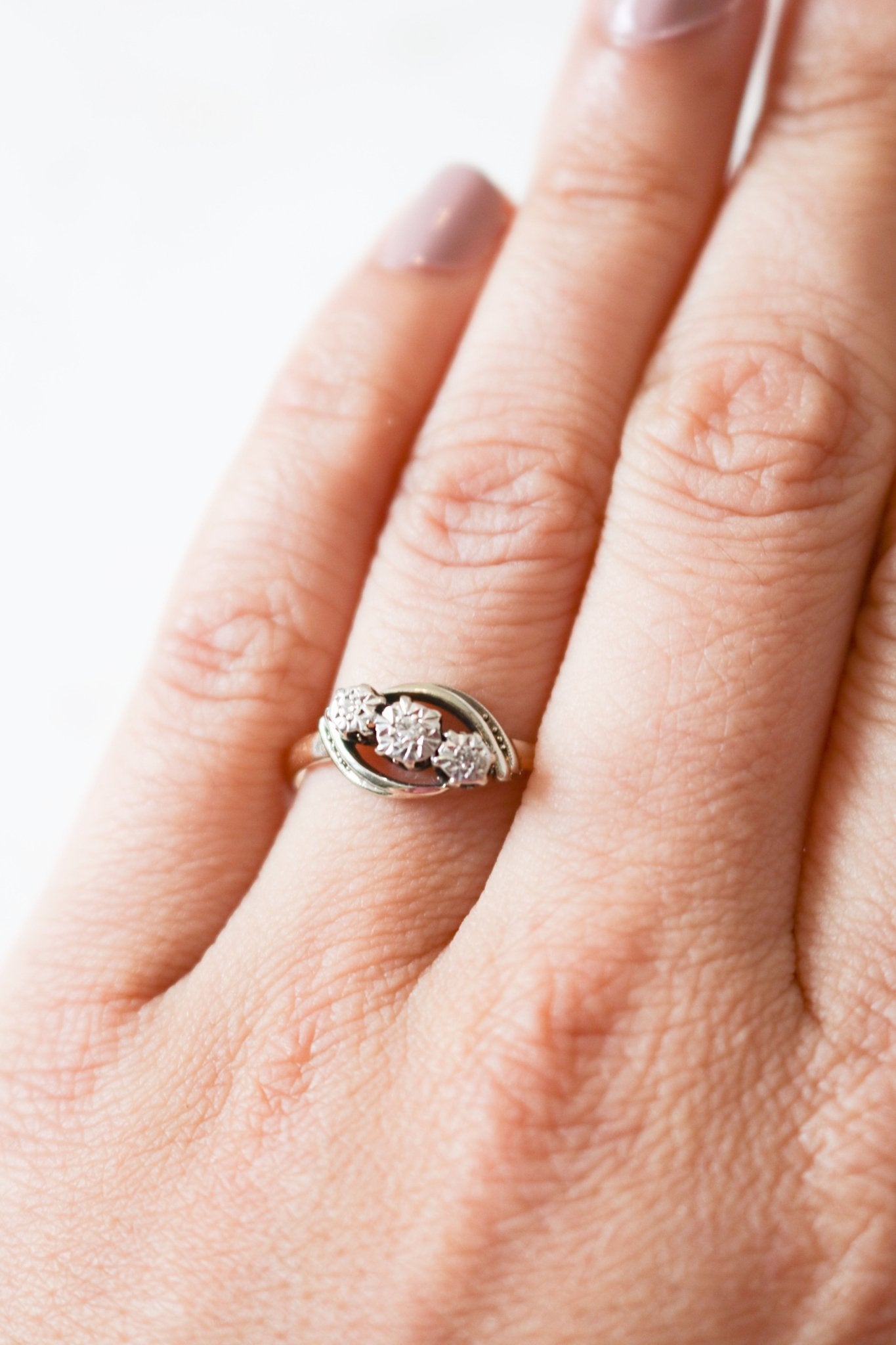 A vintage engagement ring in 18ct gold and platinum with diamonds is worn on a finger.