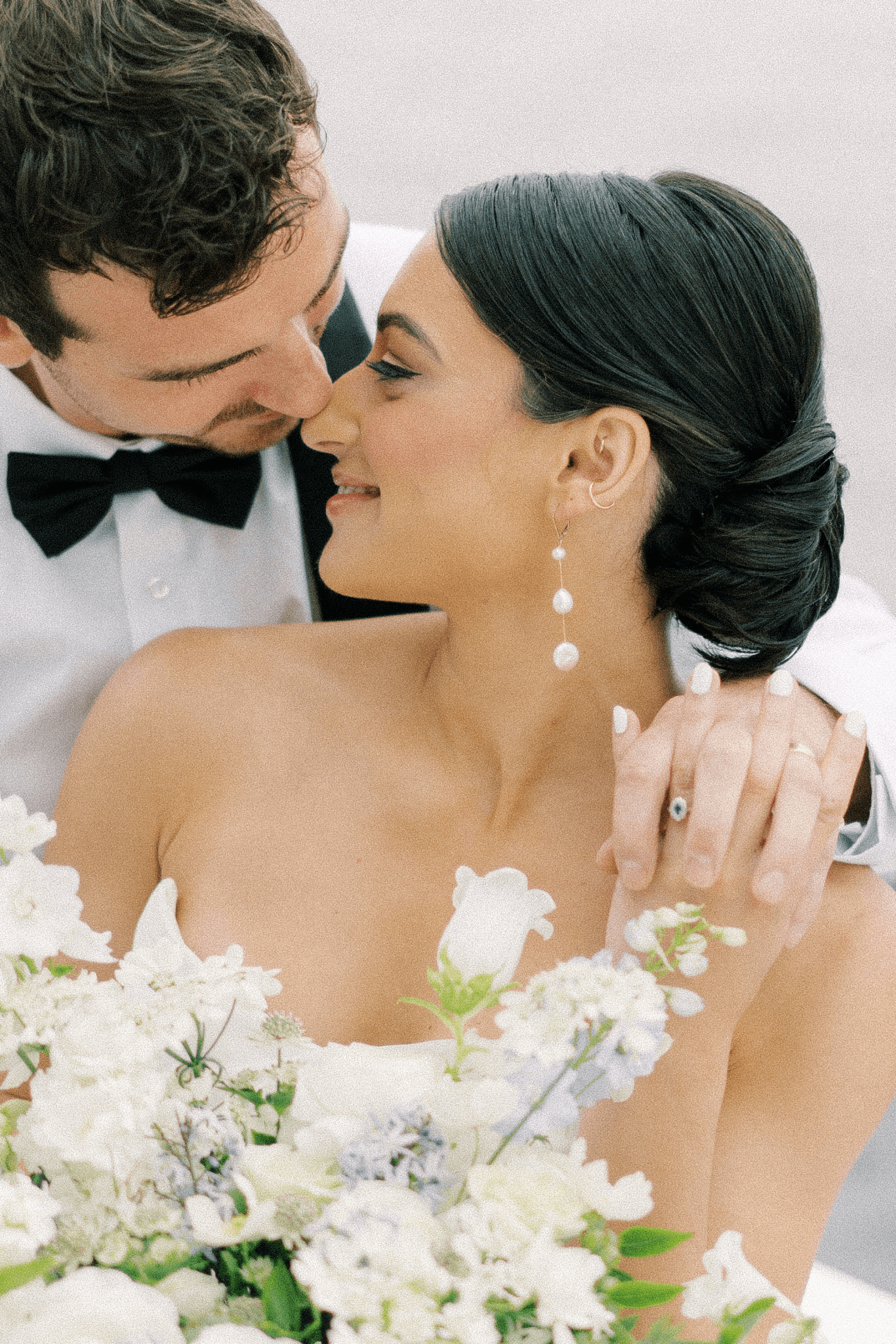 A newlywed couple share a moment together while bride wears fresh water pearl bridal earrings. 