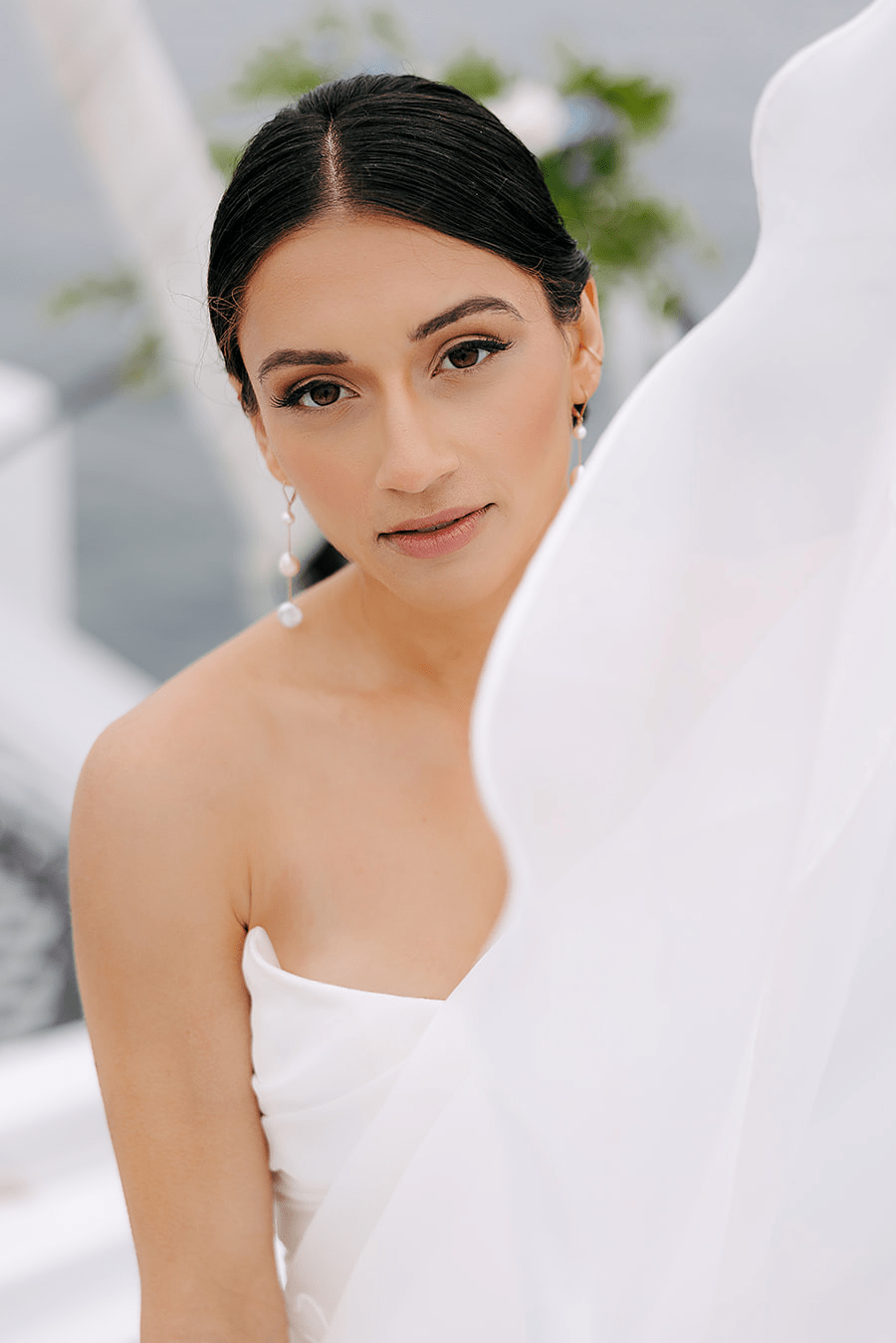 Stunning new bride in white wedding dress wearing dangle gold-filled freshwater pearl bridal earrings. 