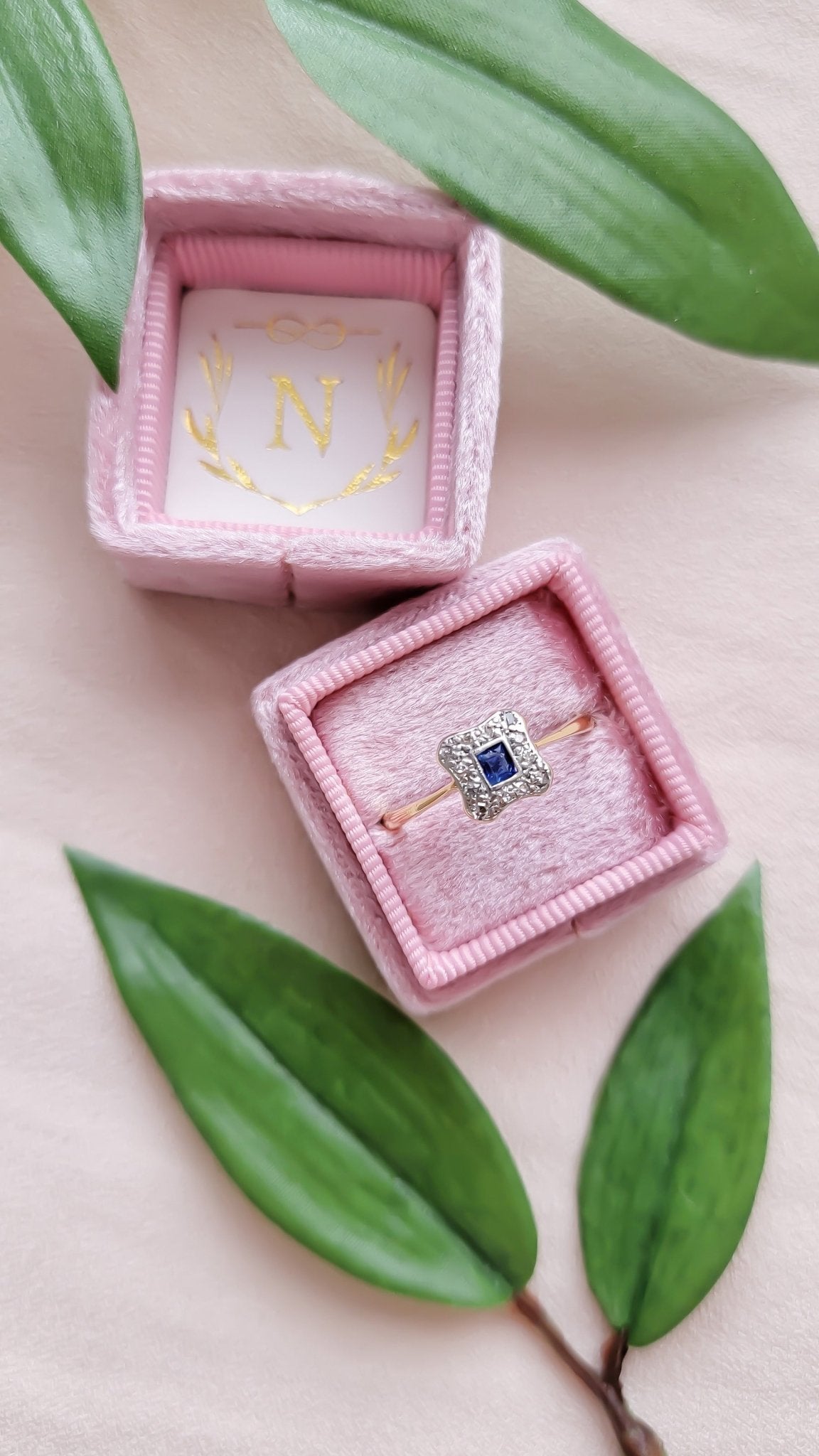 Aurora 18k Yellow Gold and Platinum Diamond Sapphire Engagement Ring Art Deco Style in light pink ring box next to leaves. Canadian vintage engagement rings. Bridal jewelry Canada. Vintage engagement rings Canada. Canadian weddings. Wedding Canada. Woman-owned Canadian jewelry brand. Canadian jewelry business. Small Canadian jewelry brands. 