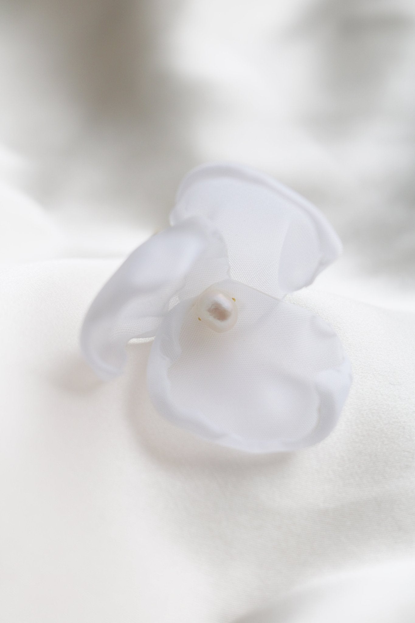 A single medium floral hairpin with a freshwater pearl is sitting on a white background. 