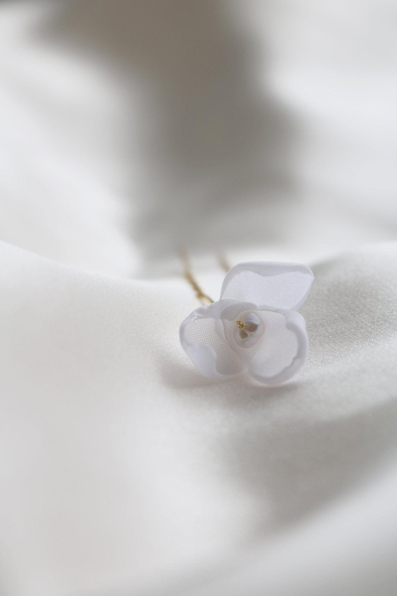 A Single Mini Averie Floral Hairpin with fabric petals and freshwater pearl for bridal accessories on white backdrop. 