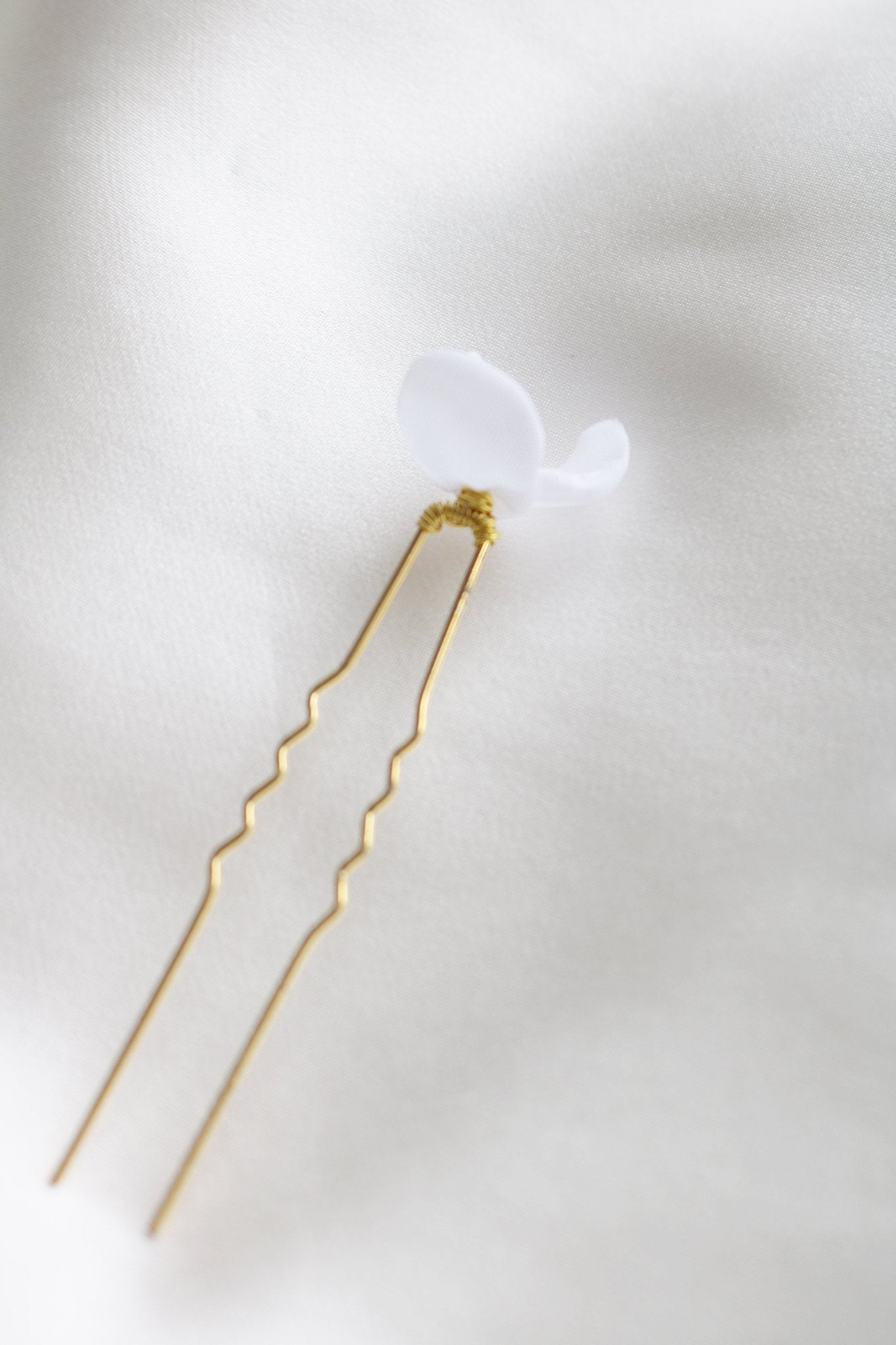 Bottom view of gold floral mini bridal hairpin with organic pearls on white backdrop. 