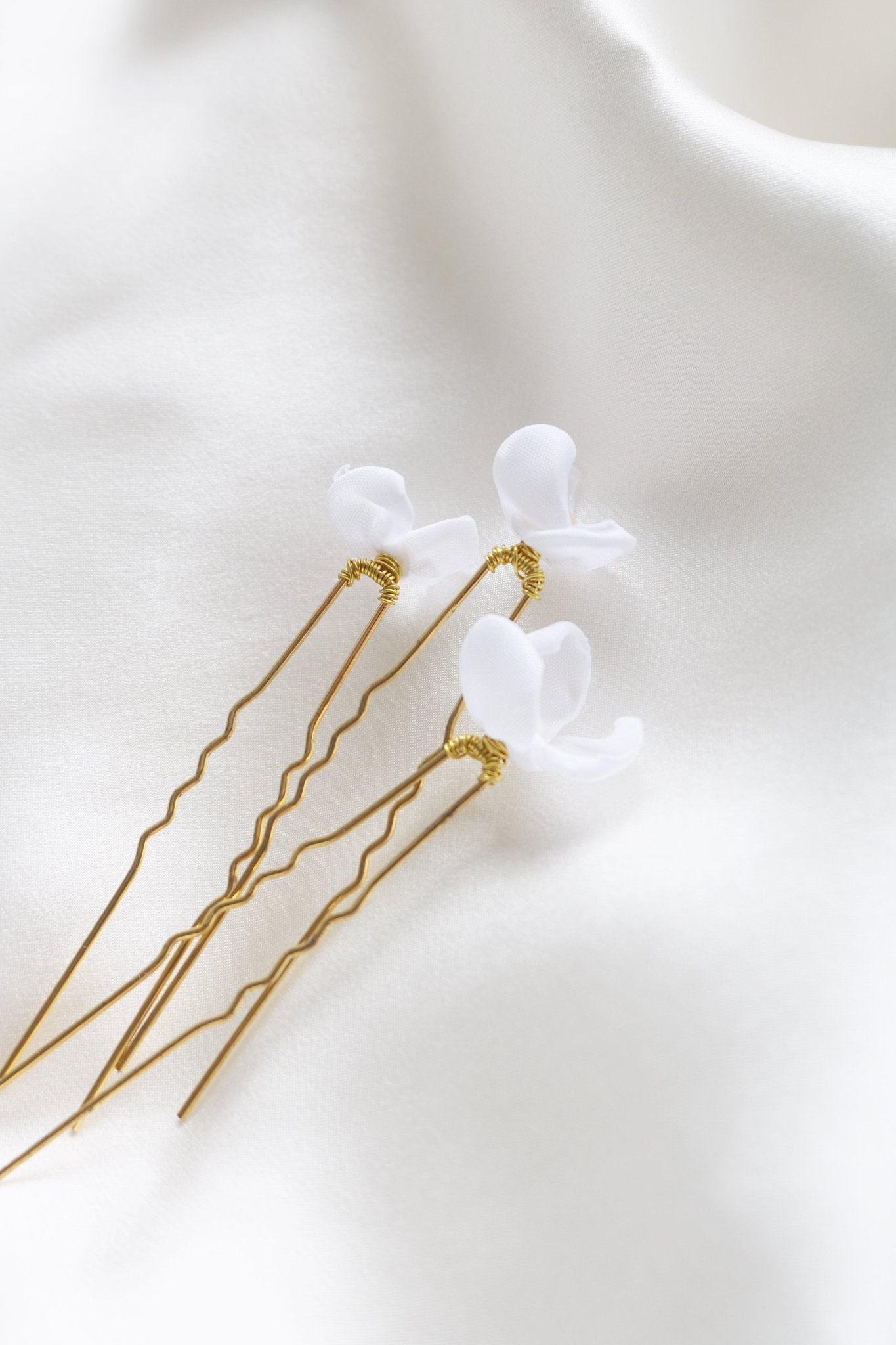 Bottom view of gold floral mini bridal hairpins with organic pearls on white backdrop. 