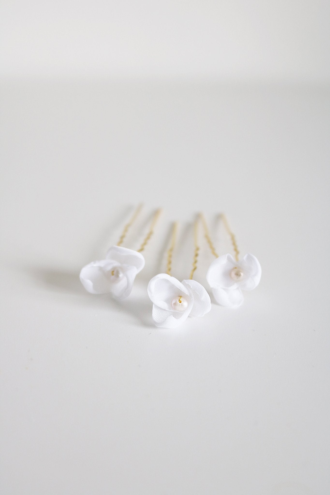 Front view of gold floral mini bridal hairpins with organic pearls on white backdrop. 