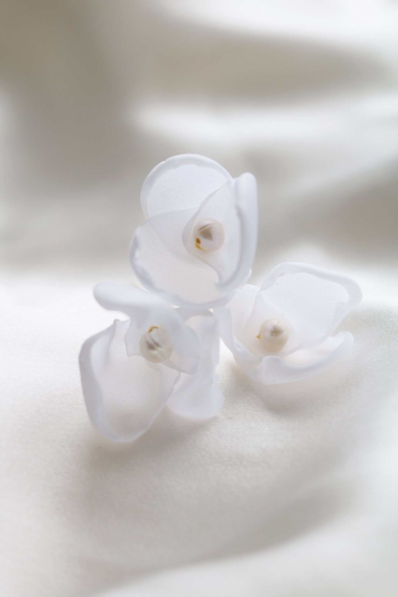 Close up of gold floral small bridal hairpins with organic pearls on white backdrop. 