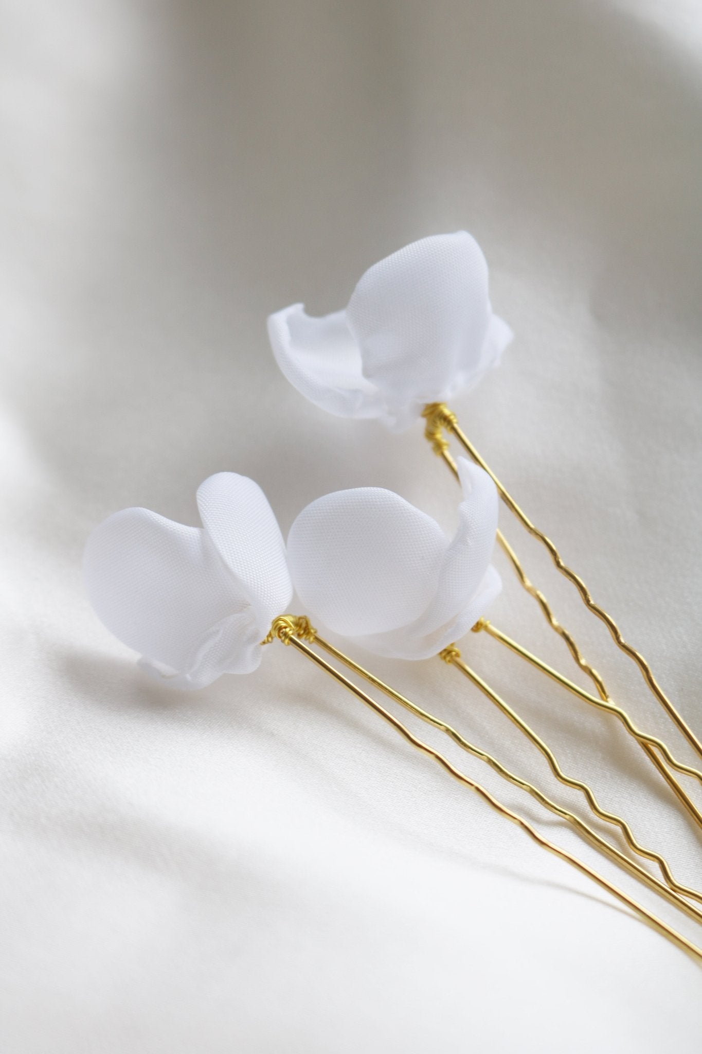 Bottom view of gold floral small bridal hairpins with organic pearls on white backdrop. 