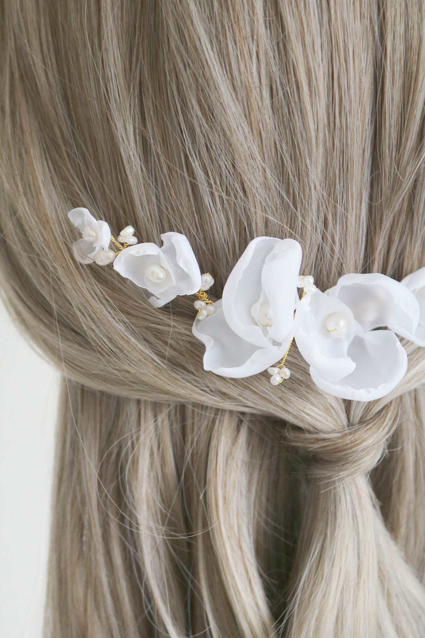 Close up of a gold freshwater pearl bridal hair comb set in a loose half ponytail hairdo. 