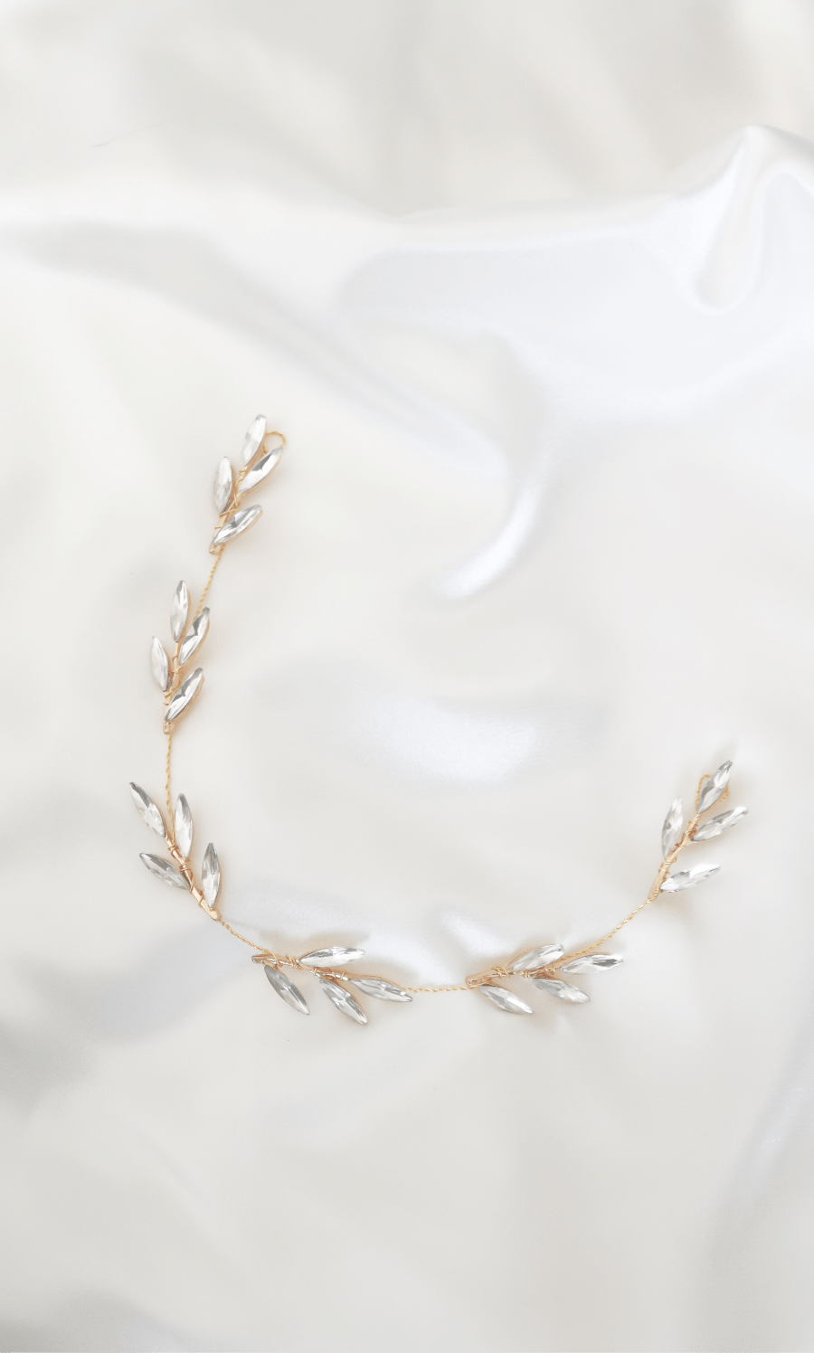 Aviana Golden Crystal Hairvine lays on a satin fabric. Bridal Hair Accessories. Bridal Accessories. Canadian Bridal Accessories. Handmade Canadian Accessories. Canadian handmade Accessories. Canadian weddings. Wedding Canada. Bridal Hairvines.