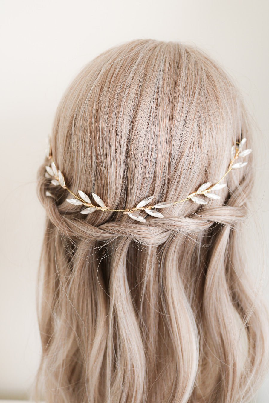 Bridal hair piece made with golden wire wrapping around crystal leaves. It sits in a bed of golden locks. 