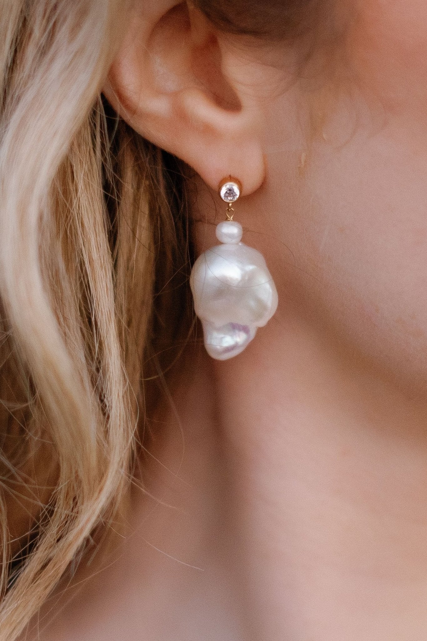 Close up of a freshwater pearl baroque earring in an ear. 