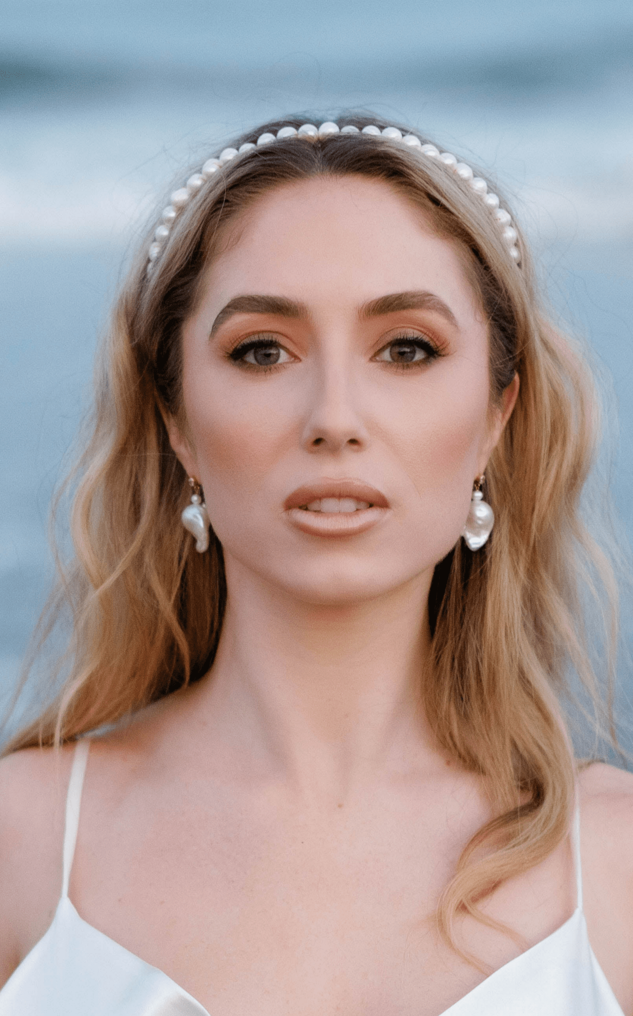 A bride wearing Baroque freshwater bridal earrings and a pearl headband. 