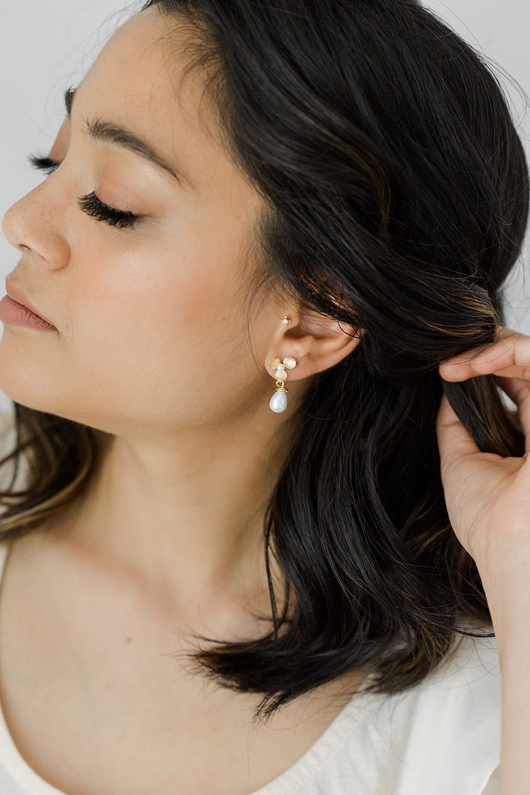 A bride dons hand-formed gold-filled flower earrings with a freshwater drop pearl and sterling silver ear posts. 