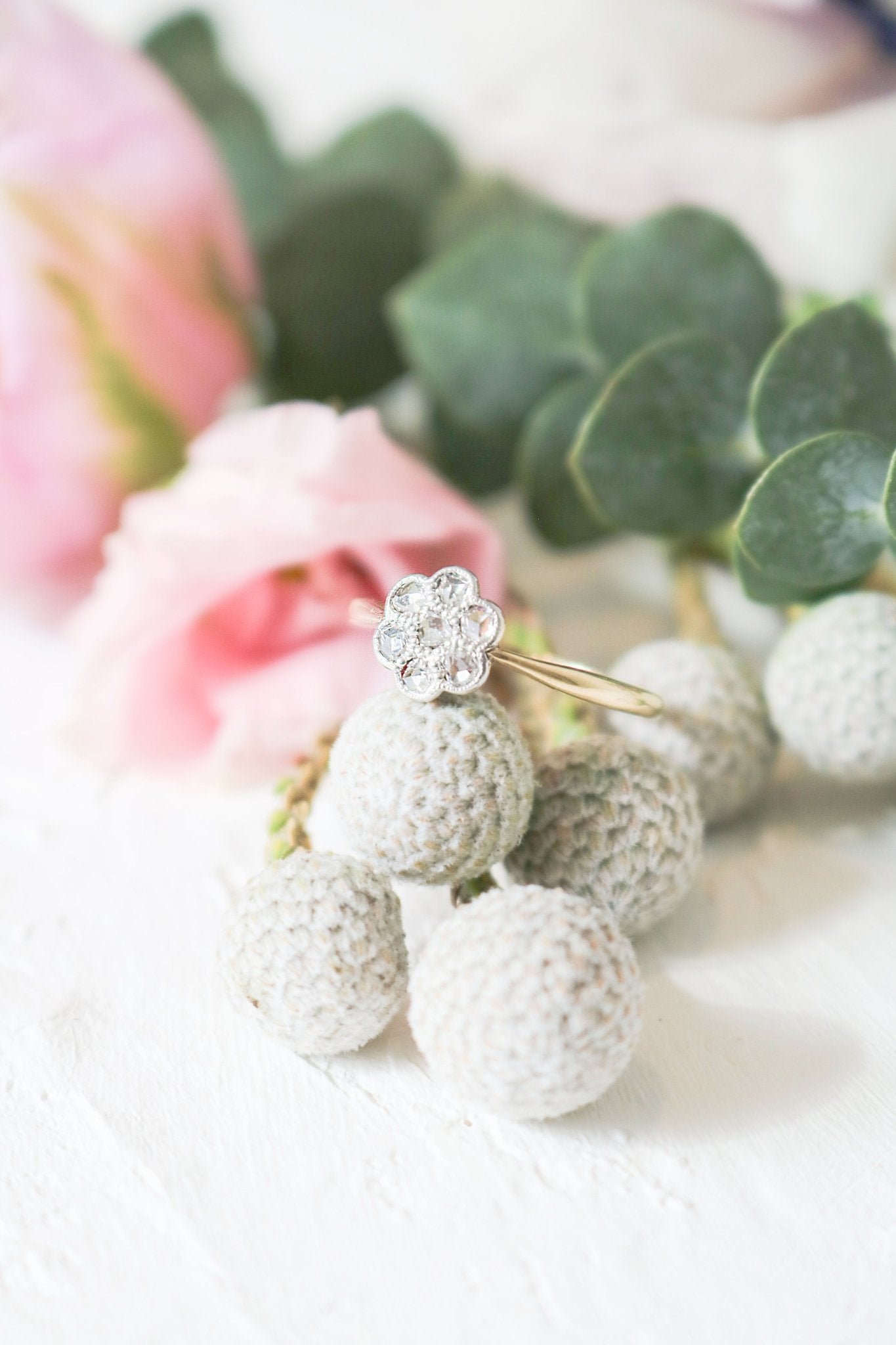 Betony Diamond Flower Vintage Engagement Ring in 18ct Yellow Gold and Platinum sitting on fake flora.