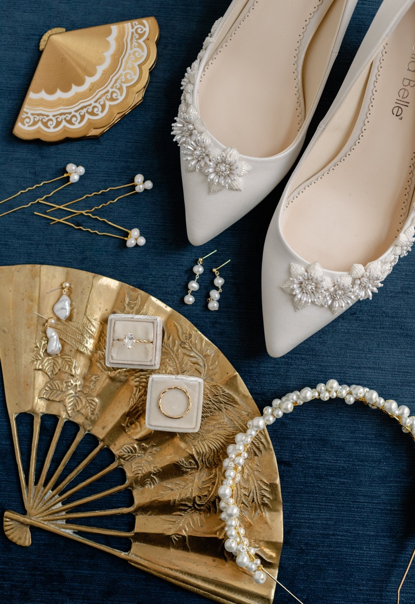 A mix of several bridal collection pieces including gold earrings, rings, bridal headband, and wedding shoes. 