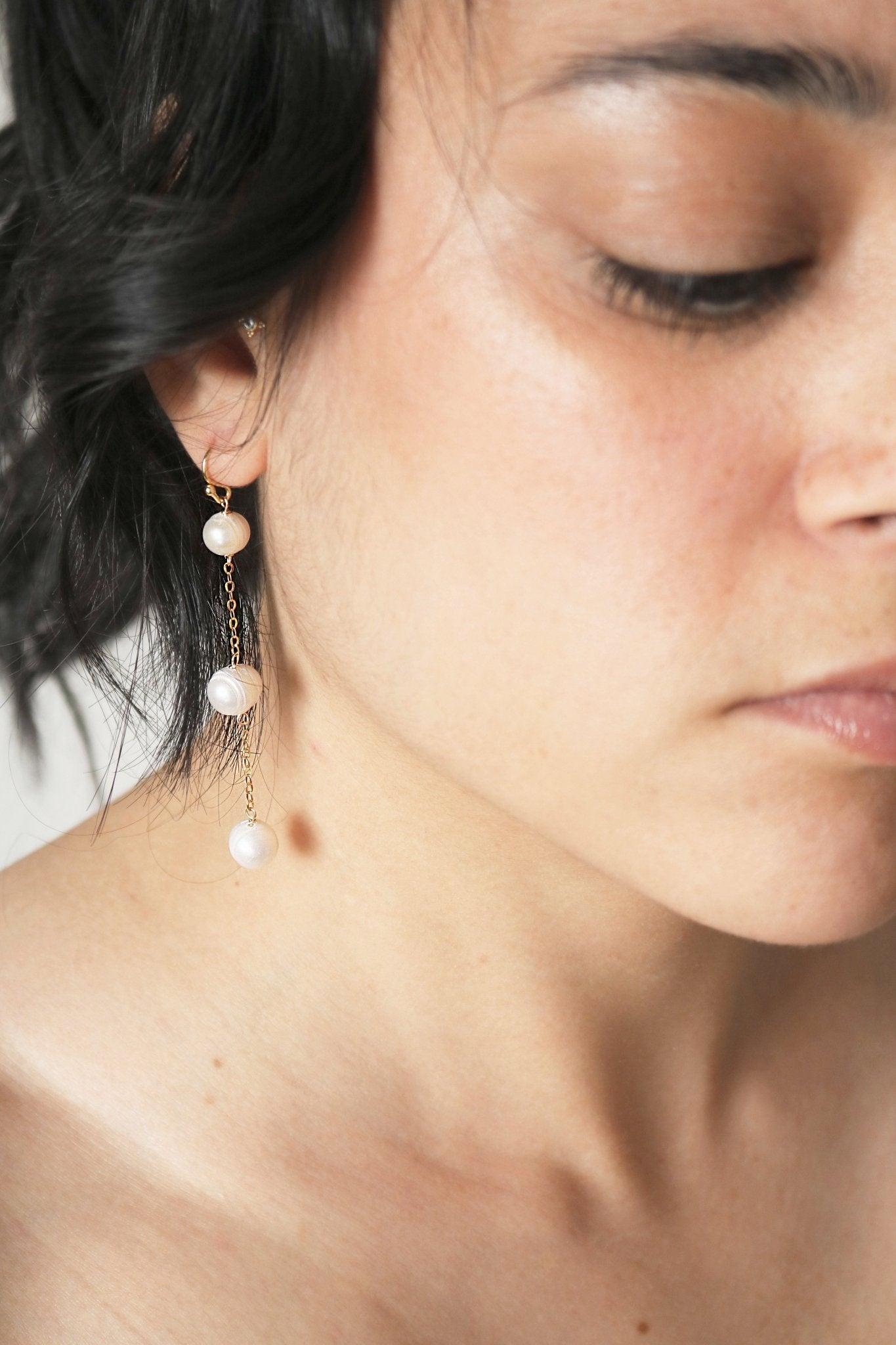 Gold-filled Bubble Fresh Water Pearl Earrings Dangle from an ear.