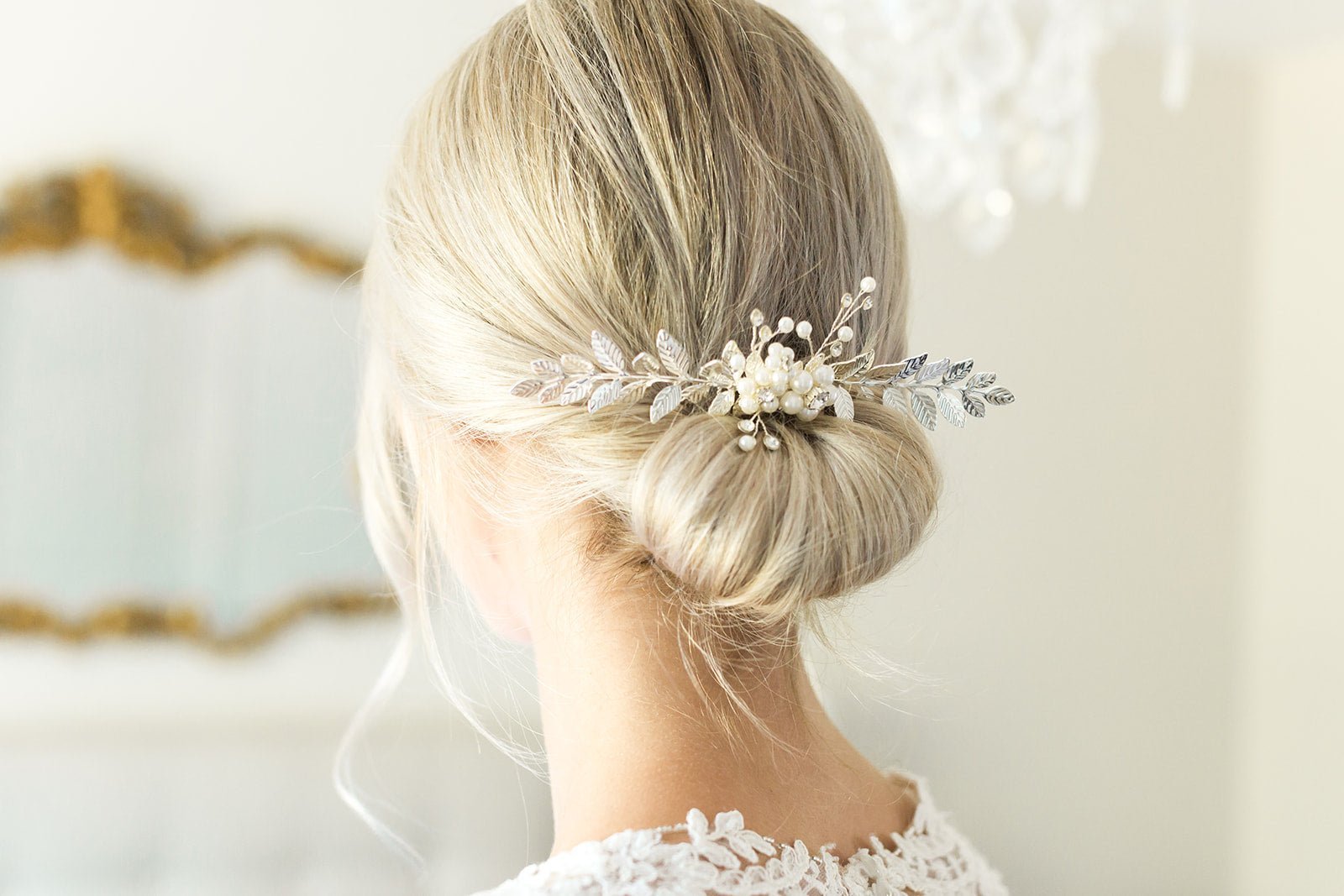 A bride showcases her silver freshwater pearl and crystal leaf wedding hair accessory tucked into a bun.