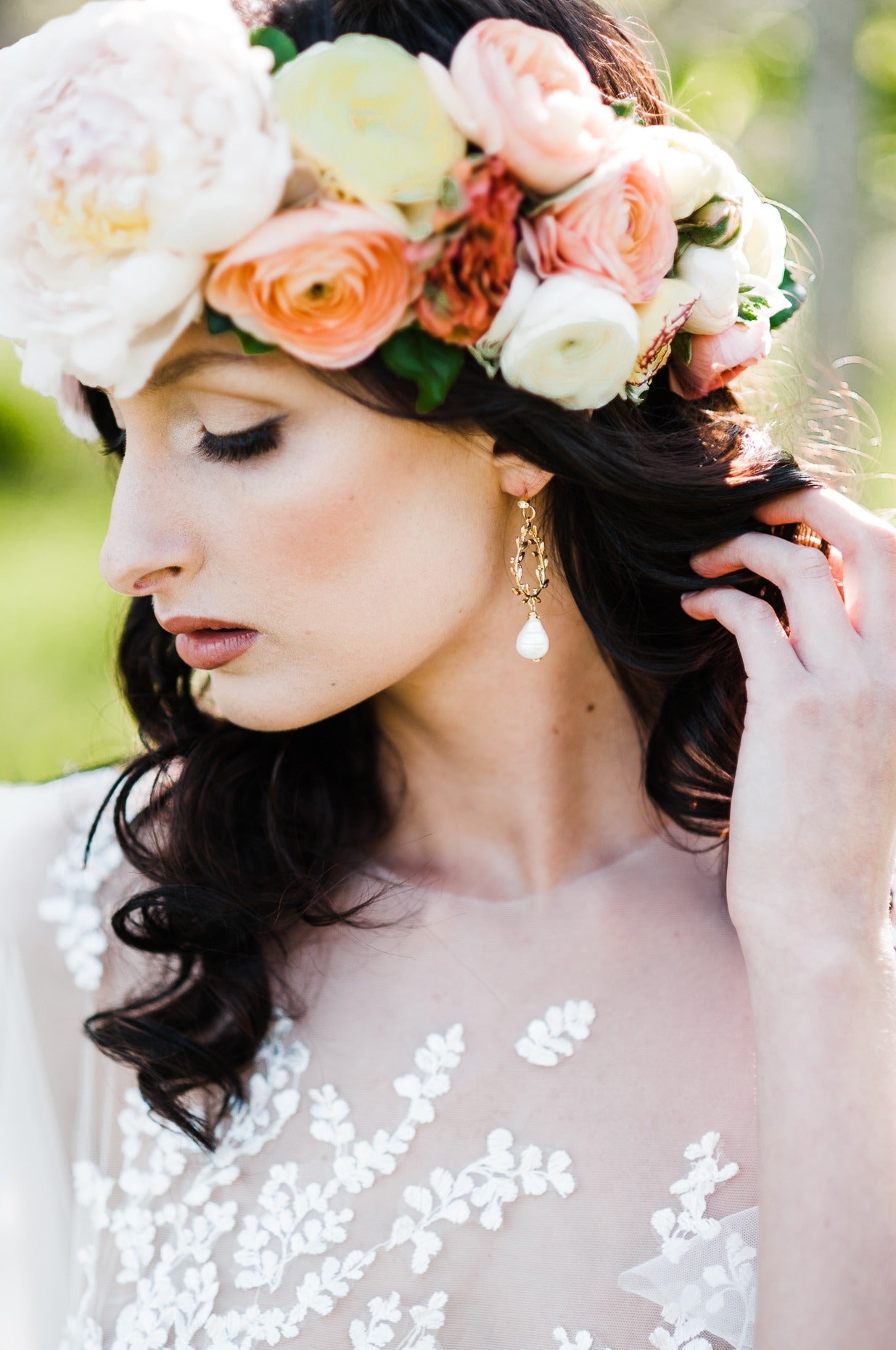 A blooming bride with a flower wreath lightly holds back her hair to bring attention to the gold-filled laurel leaf bridal earrings with freshwater pearl drops and crystal studs. Bridal jewelry Canada. Pearl jewelry Canada. Pearl Bridal jewelry Canada. Gold-filled jewelry Canada. Organic pearl jewelry. Canadian jewelry brands.  