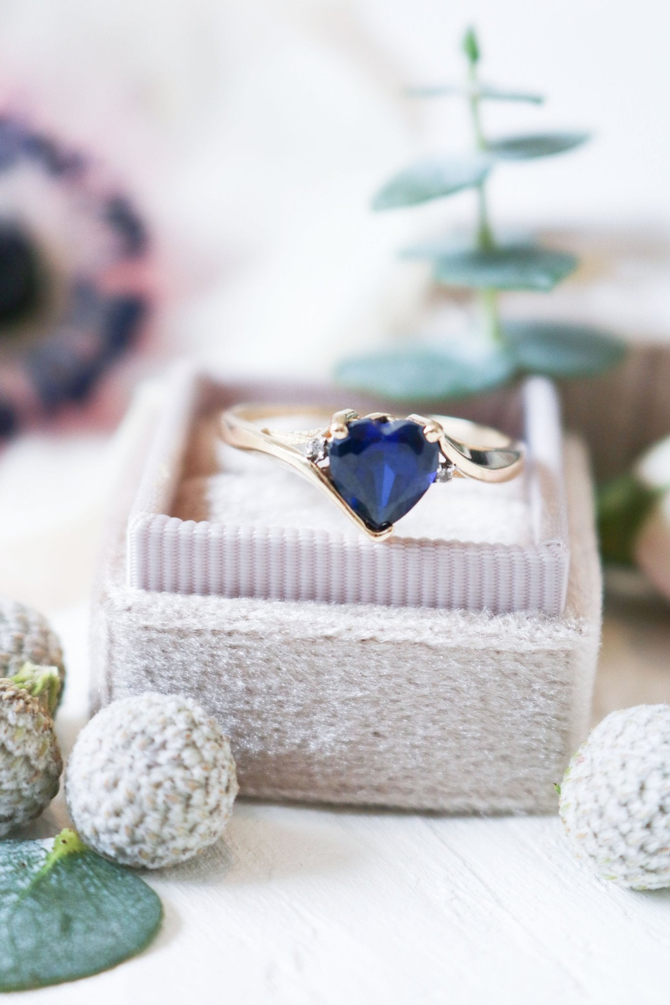 A close up of a Sapphire Heart and Diamond Vintage Engagement Ring in 9ct Gold is displayed on top of a ring box. 