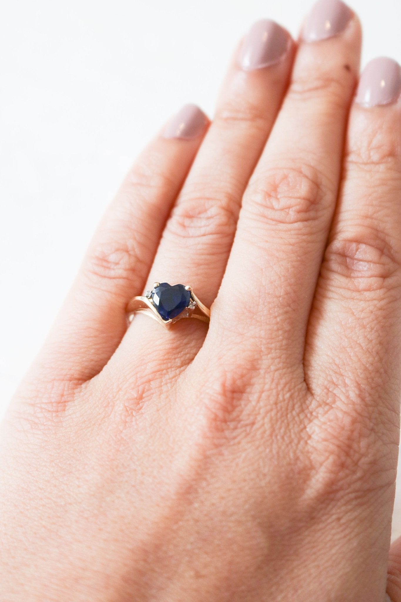 Celia Sapphire Heart and Diamond Vintage Engagement Ring in 9ct Gold worn on a ring finger.