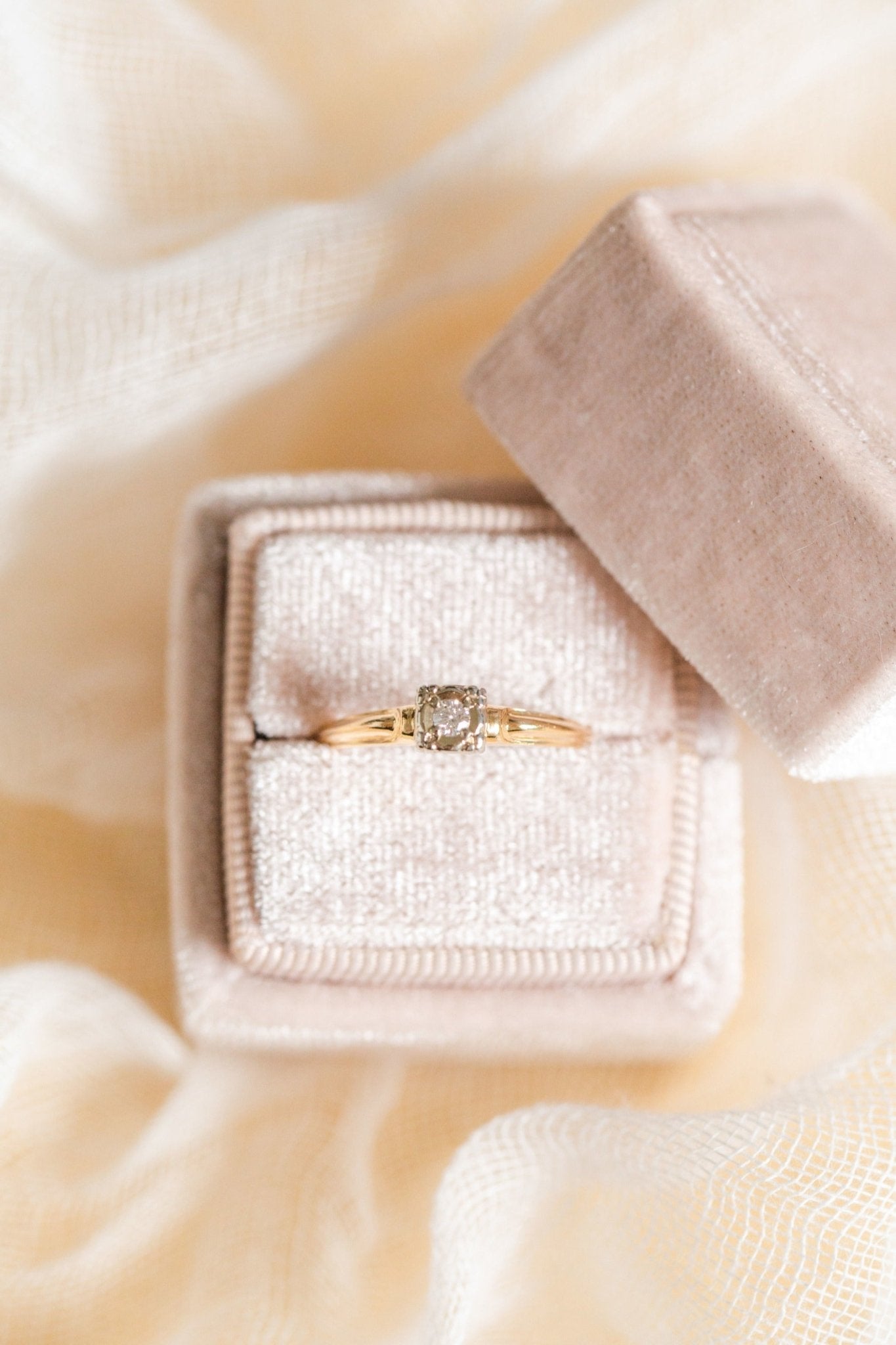 An Art Deco style 14k Gold vintage engagement ring with diamond sits in a ring box.