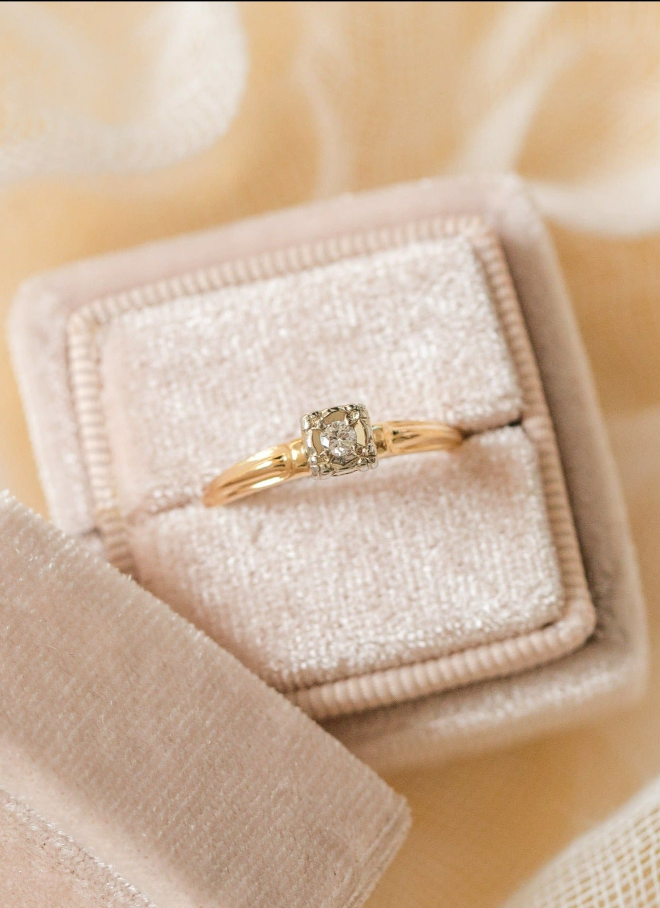 A close up of a 14k Gold Diamond Vintage Engagement Ring sitting in a ring box with its top leaning against it. 