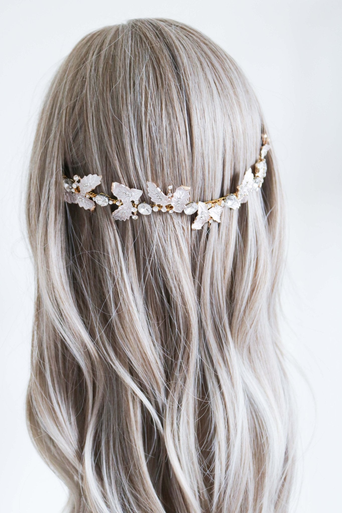 Detailed gold bridal headband with leaves and crystals set back in long wavy hair.