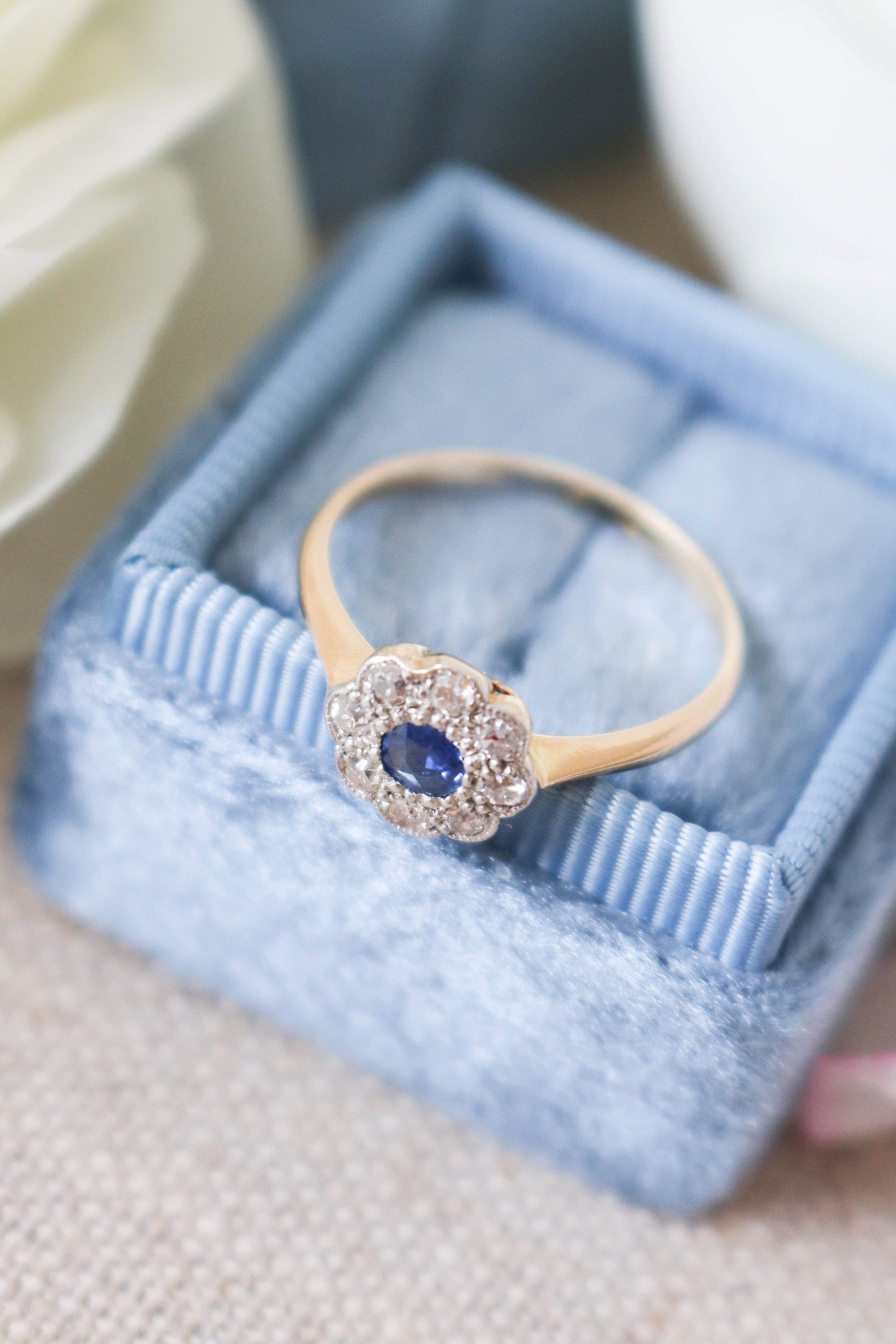 A close up top view of a 18k Yellow and White Gold Vintage Sapphire and Diamond Engagement Ring on top of a powder blue ring box. 