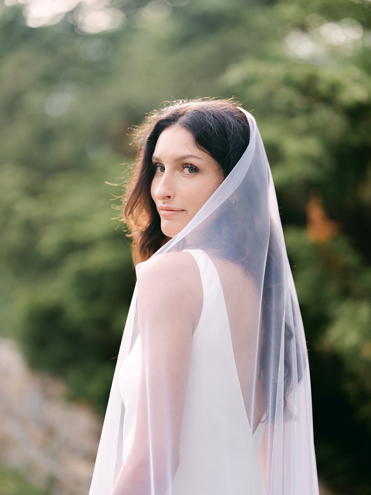 A bride looking over her shoulder while wearing the Darling Romantic Wedding Veil. Canadian weddings. Wedding Canada. Wedding veils Canada. Bridal Hair Accessories. Bridal Accessories. Canadian Bridal Accessories. Handmade Canadian Accessories. Canadian handmade Accessories. Canadian designer. Canadian artist.