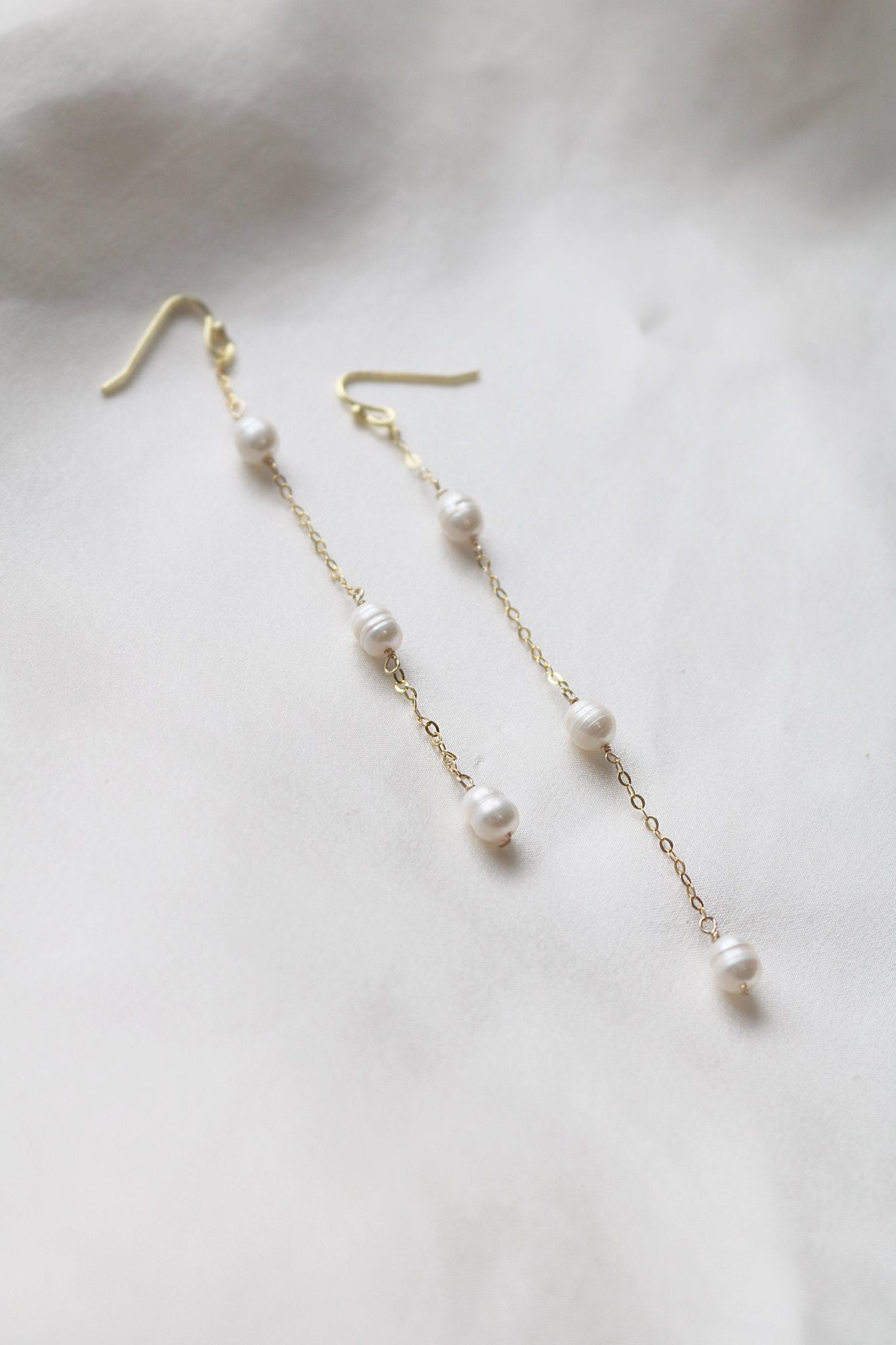 A pair of Dew Drop Fresh Water Pearl Earrings in Gold Filled sits against a white background. 