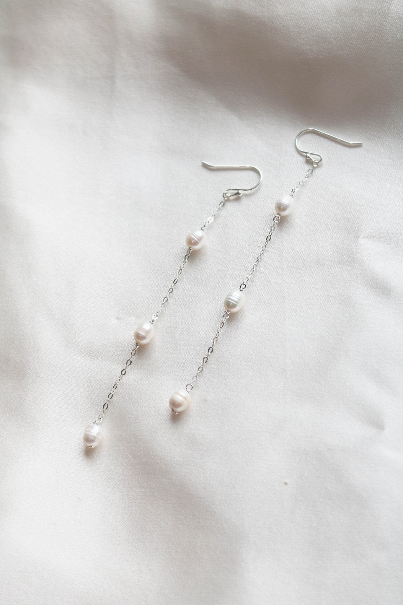 Sterling Silver Dew Drop Fresh Water Pearl Earrings on a White Cloth. 