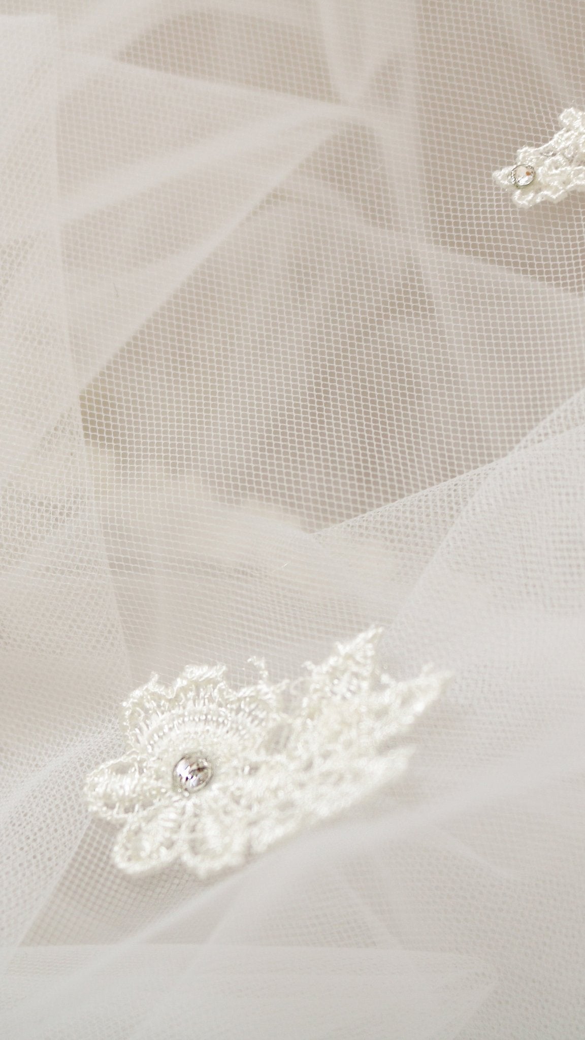 Extreme close up of a detailed embroidered lace flower on sheer tulle wedding veil. 