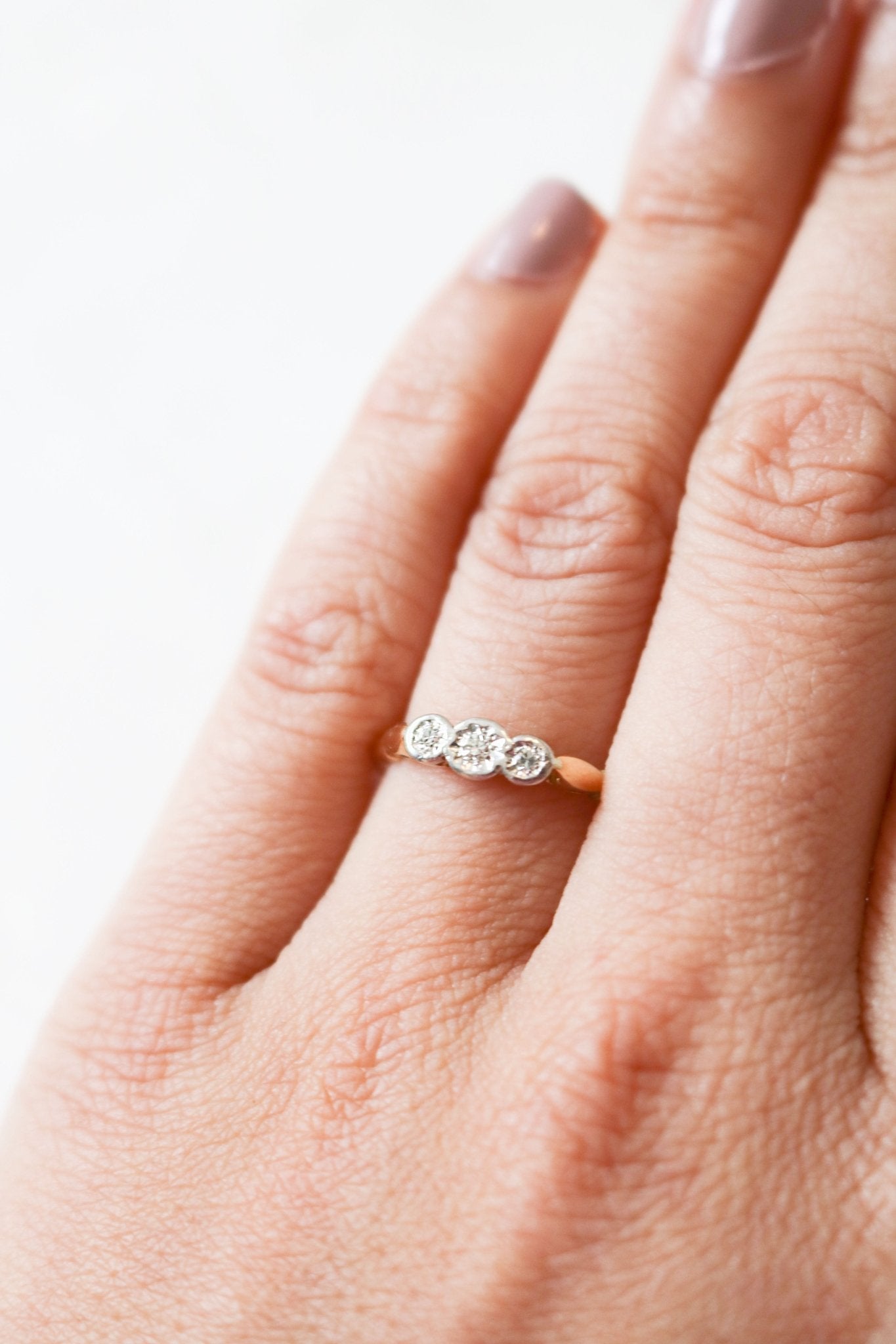 An 18ct Gold and Three Diamond Vintage Engagement Ring sits on a ring finger. 