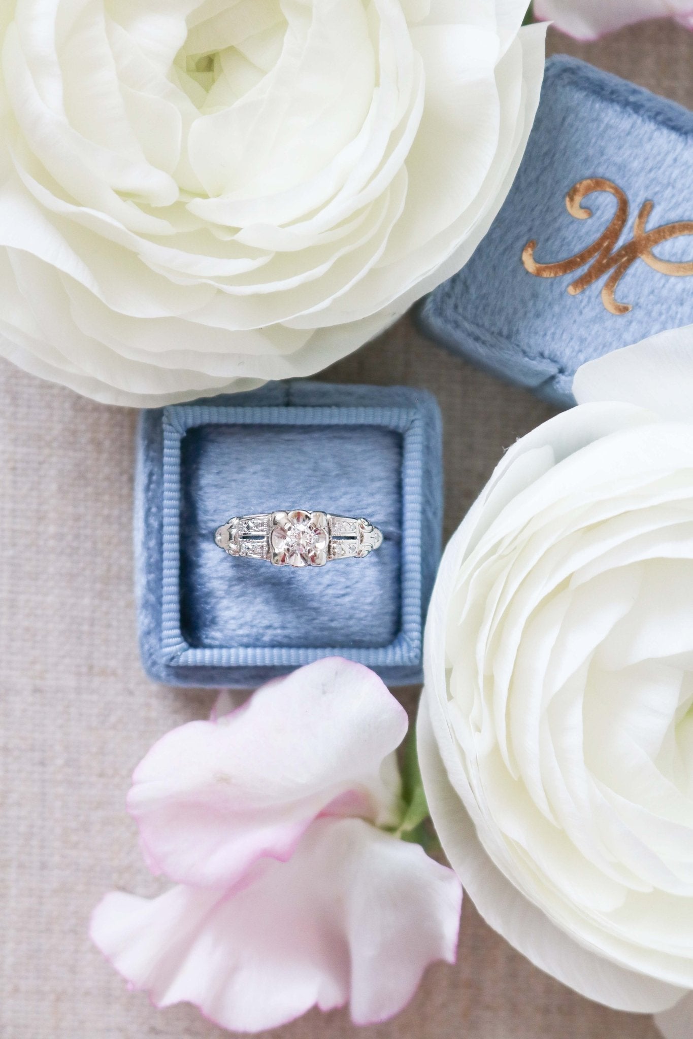 Elena Diamond Vintage Engagement Ring in 14k White Gold sits in a ring box surrounded by flowers. 