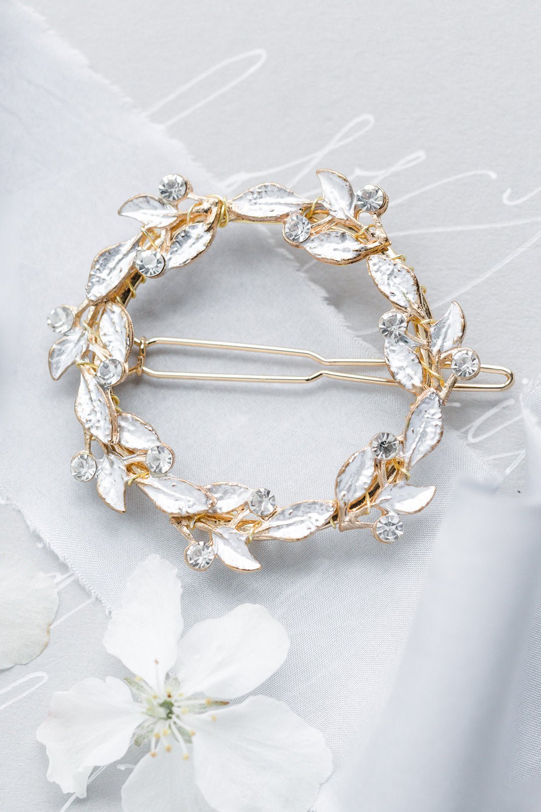 Full Golden wreath bridal barrette with leaves and crystals on a light grey surface with white fabric and flower. Handmade bridal accessories & Bridal hair accessories good for everyday wear & weddings