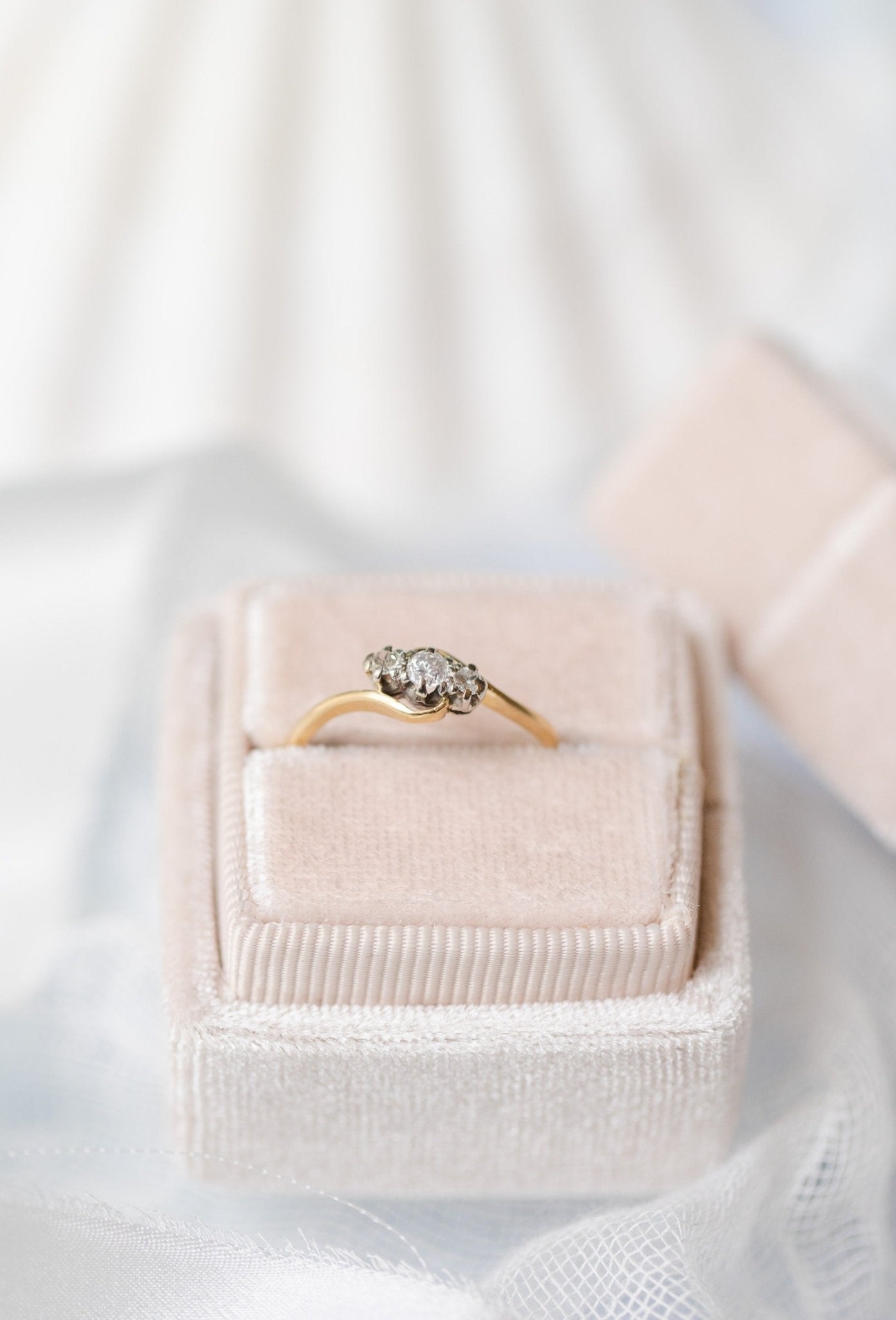 An Emilia Trilogy Diamond Engagement Ring in 18ct Gold and Platinum, c.1900 England sitting in a ring box against a white backdrop.