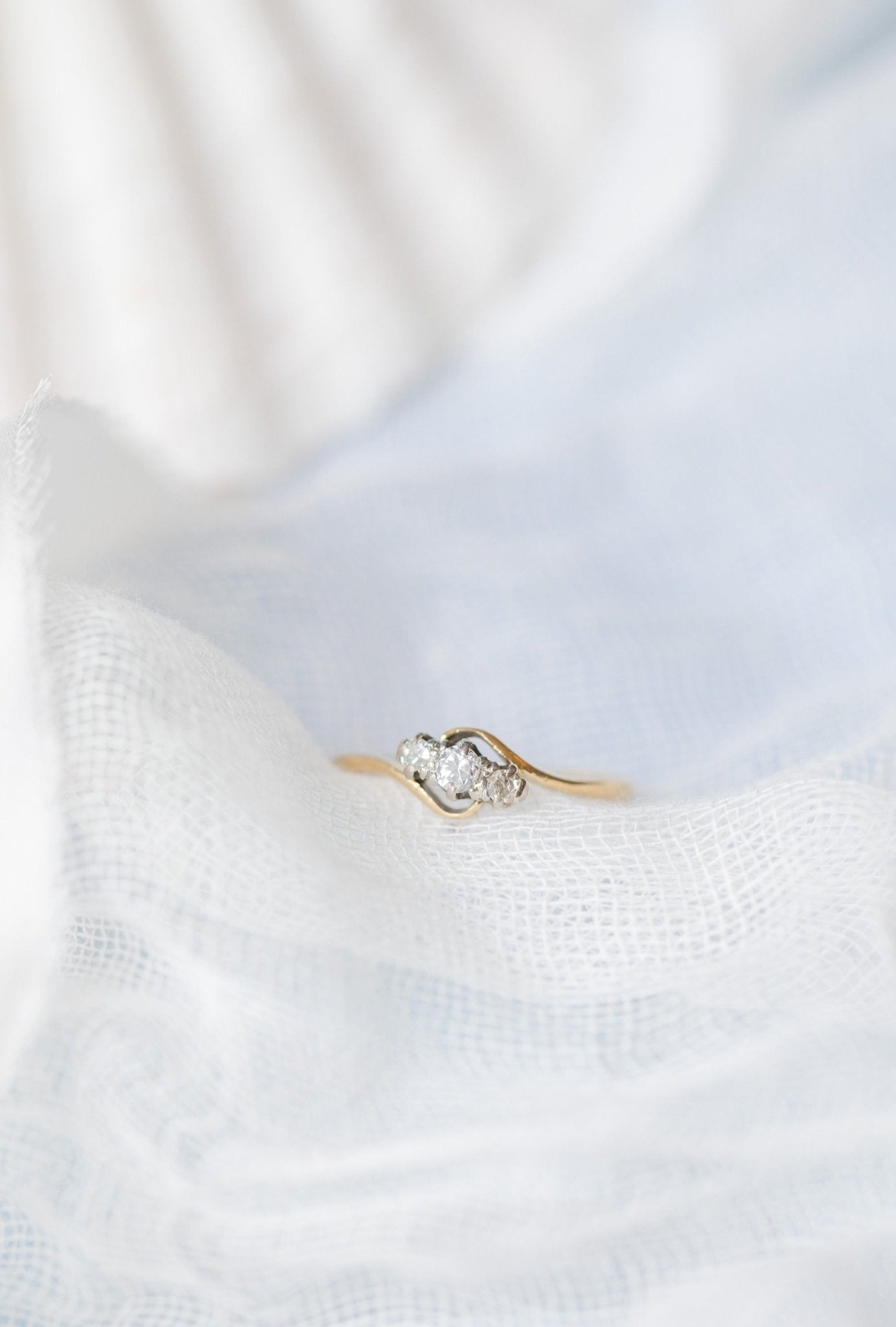 Close up of an 18ct Gold and Platinum Diamond Vintage Engagement Ring sitting on a white fabric. 