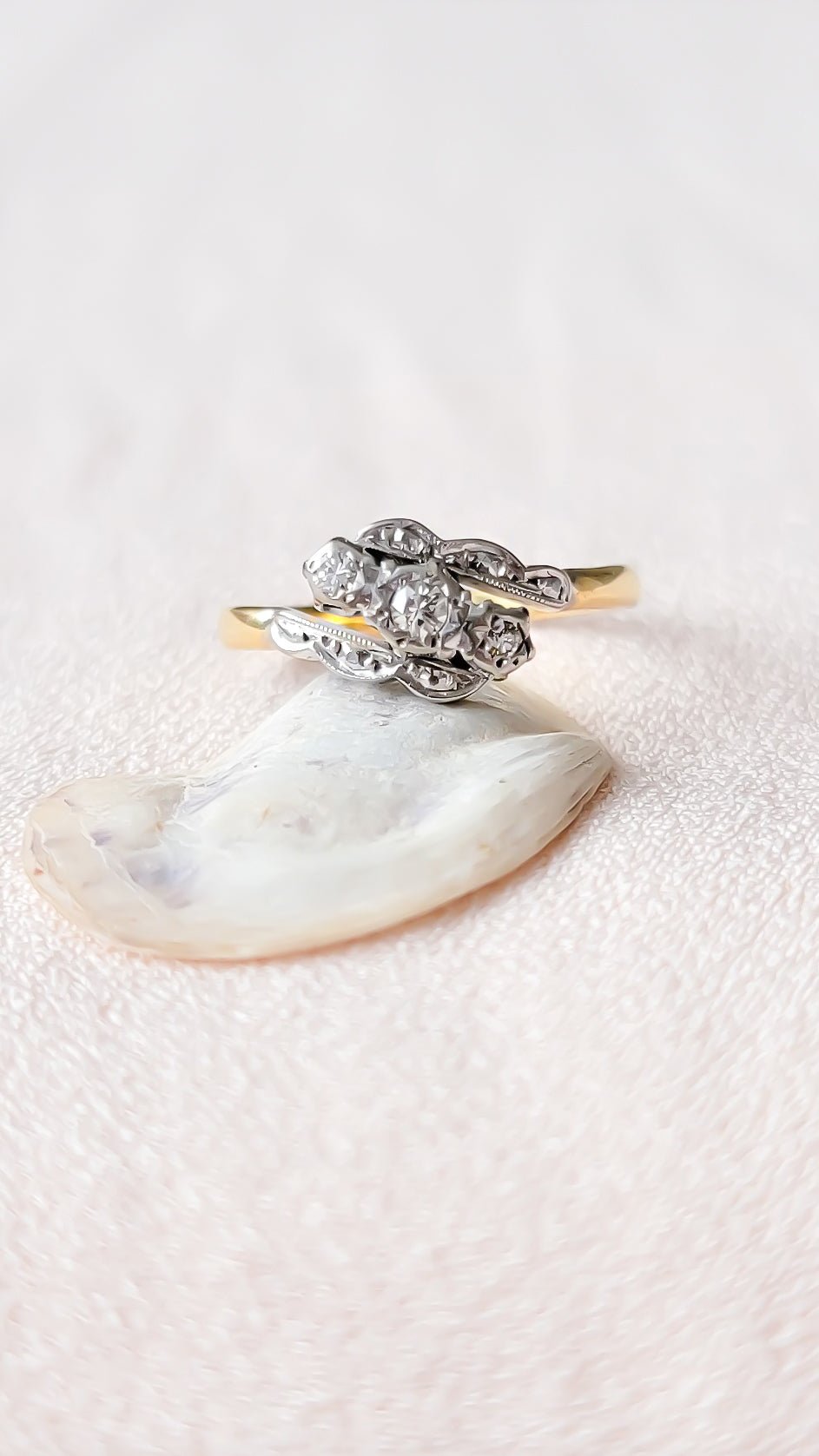An Art Deco vintage engagement ring with three diamonds set in platinum sitting on a white seashell with textured surface. Antique engagement rings Canada & Vintage rings from Small Canadian jewelry brand