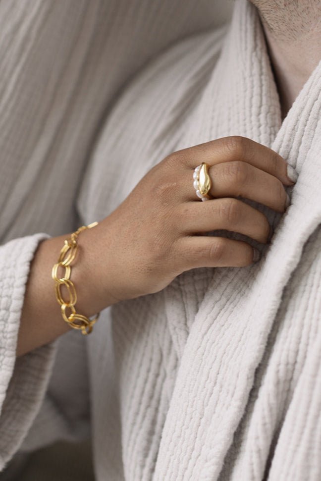 A woman's hand wearing The Everyday Freshwater Pearl Ring and gold-filled Essence Figure Ring. Gold-filled jewelry Canada. Affordable Canadian jewelry brands. Pearl jewelry Canada.