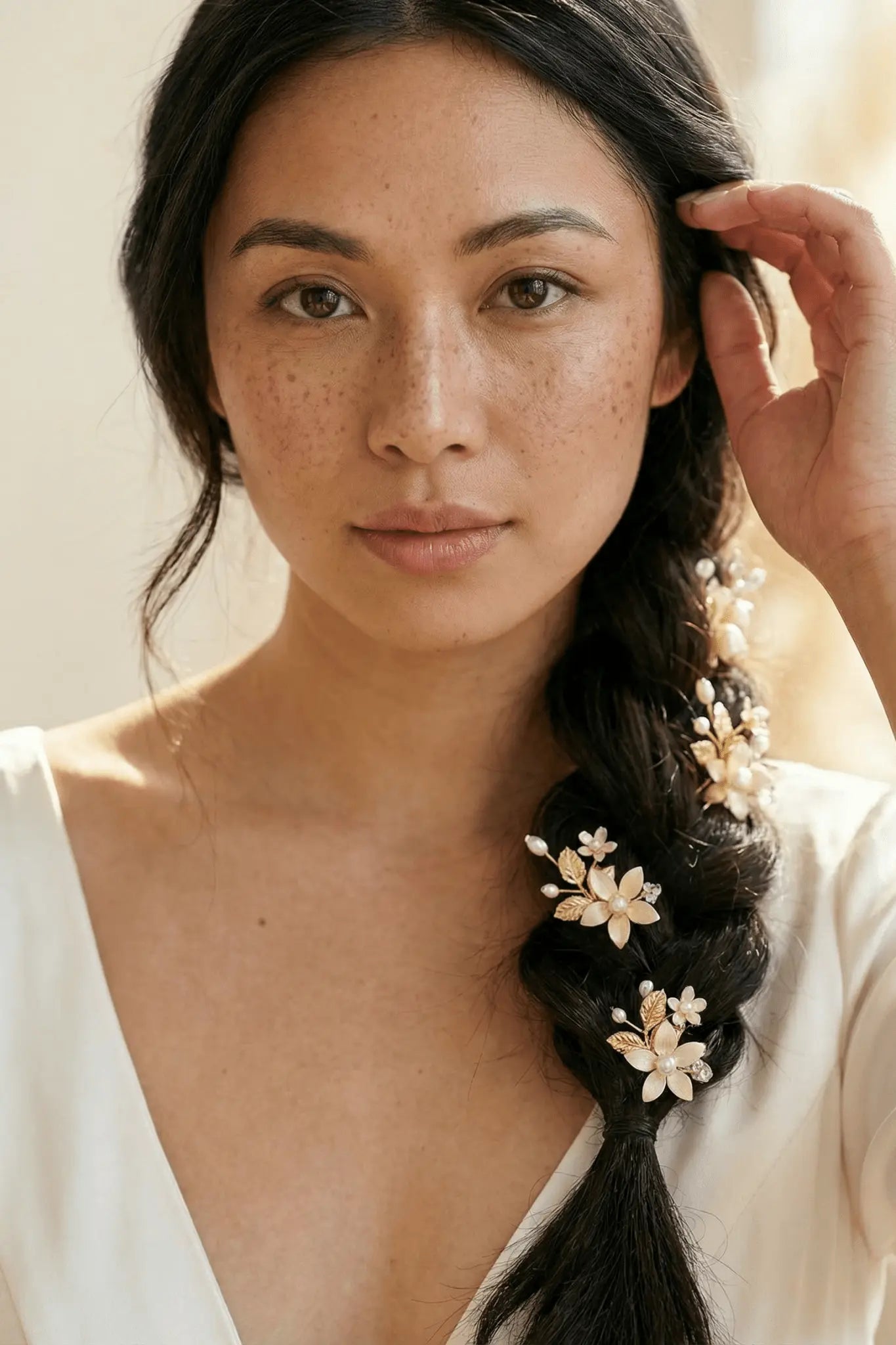 Filipina bride with a braid adorned with hand-enameled flowers, wearing a white wedding dress against a neutral background. Handmade bridal accessories and freshwater pearl hair accessories by a Canadian jewelry designer.
