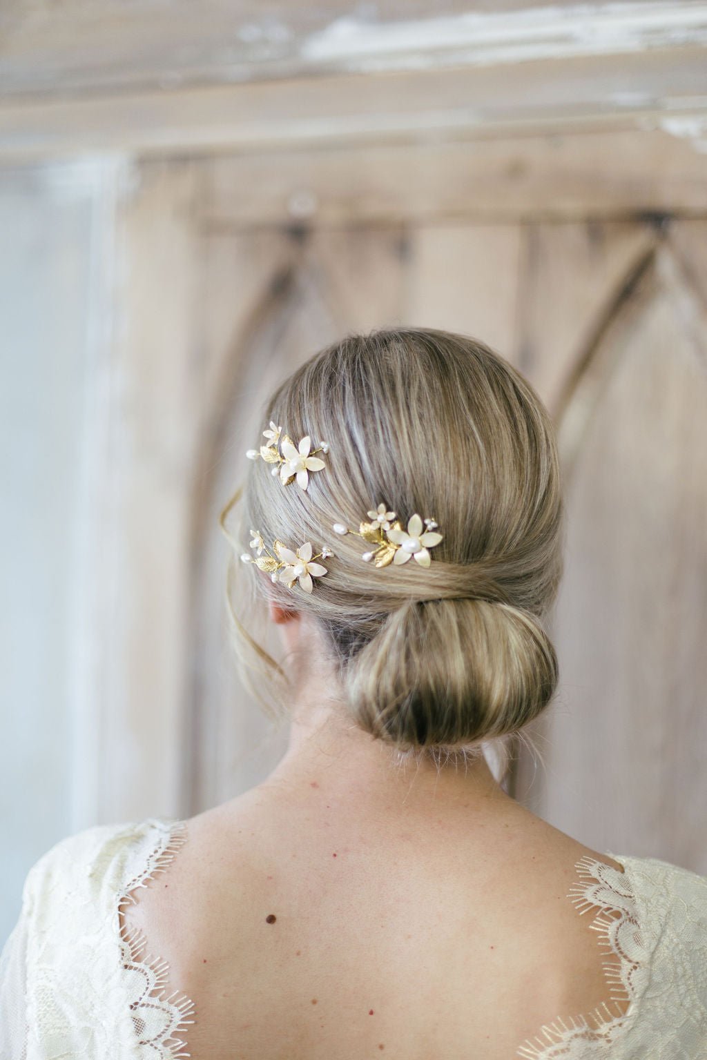 A bride by a rustic barn has an up-do holding three fancy floral hairpins with freshwater pearls. 