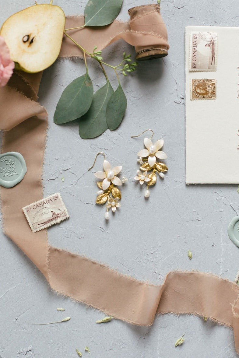 Statement gold-filled earrings with enamel flowers, golden leaves, and freshwater pearls.