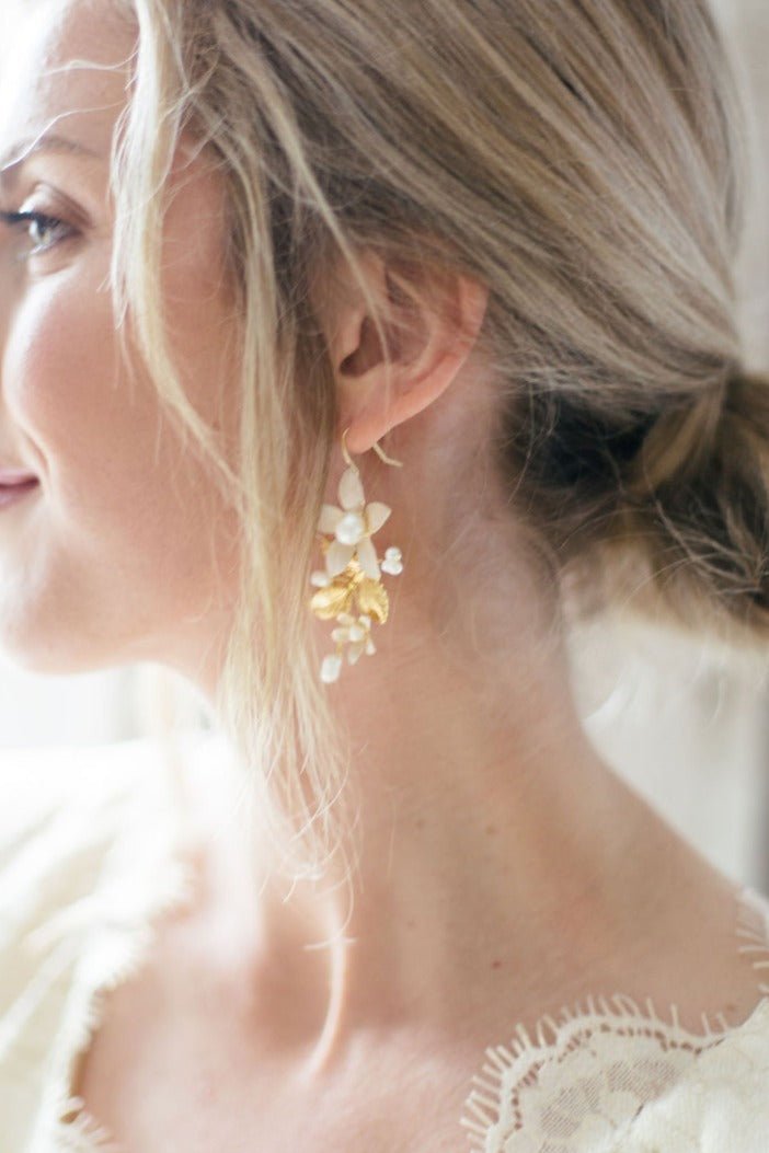 Content bride basks in the daylight glow wearing her fancy wedding earrings of gold-filled floral beauty. The freshwater pearls adding to her elegance.  