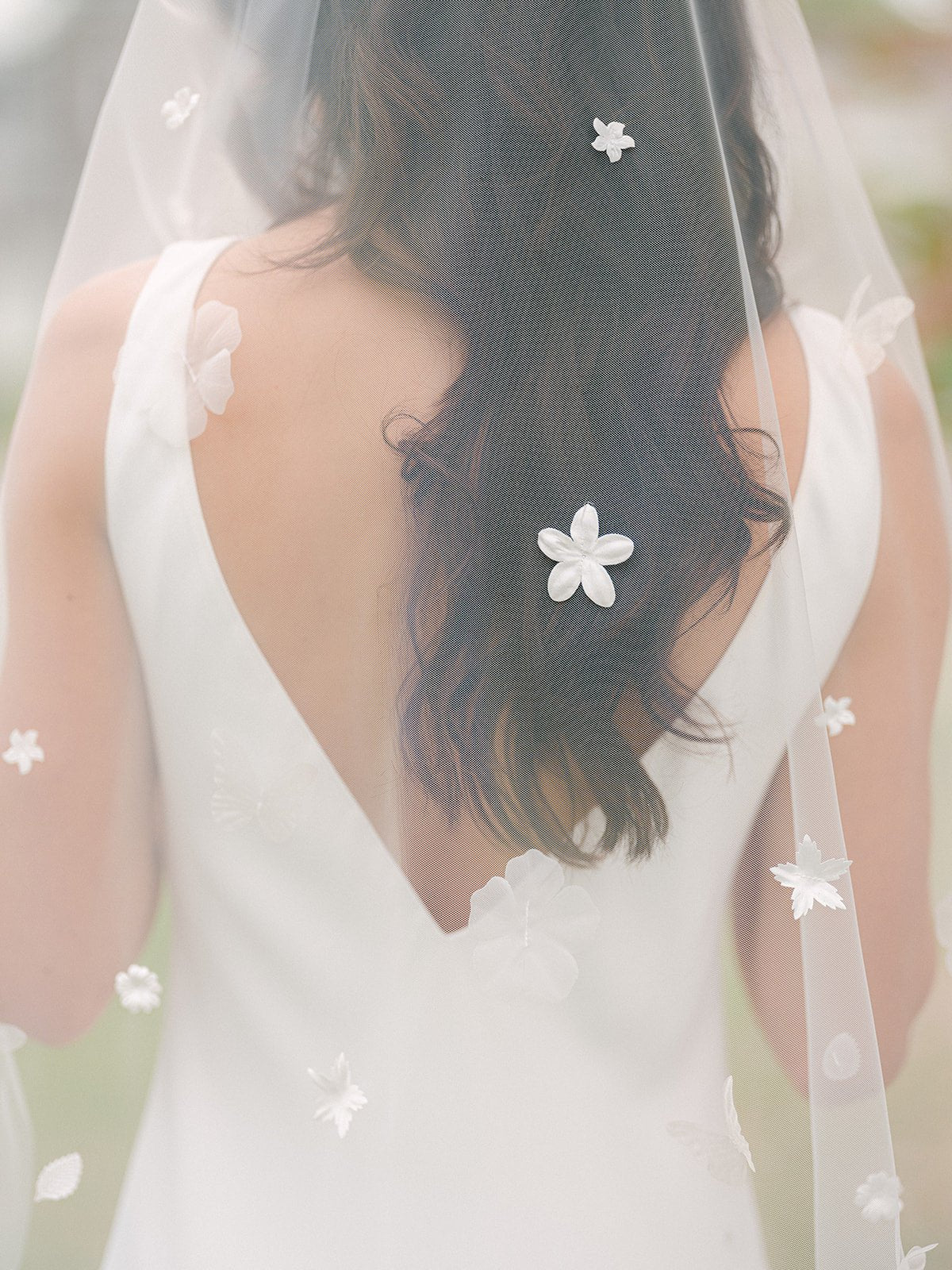 Back and up close view of a sheer tulle wedding veil with flowers and leaves. 