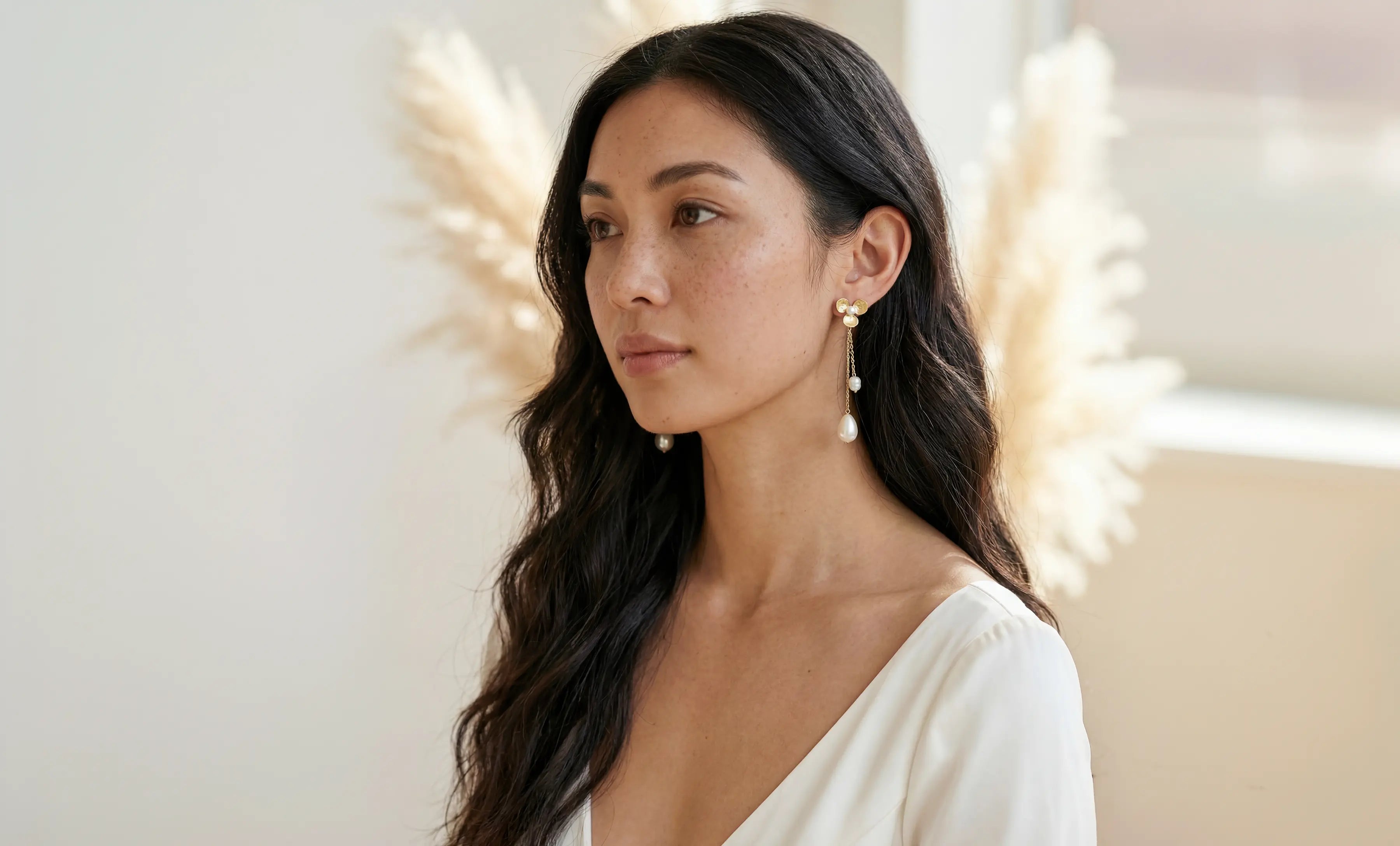 Filipino woman with long dark hair wearing floral designed fresh water pearl dangle earrings with neutral background. Affordable bridal jewelry & Organic pearl jewelry handmade by Canadian jewelry maker
